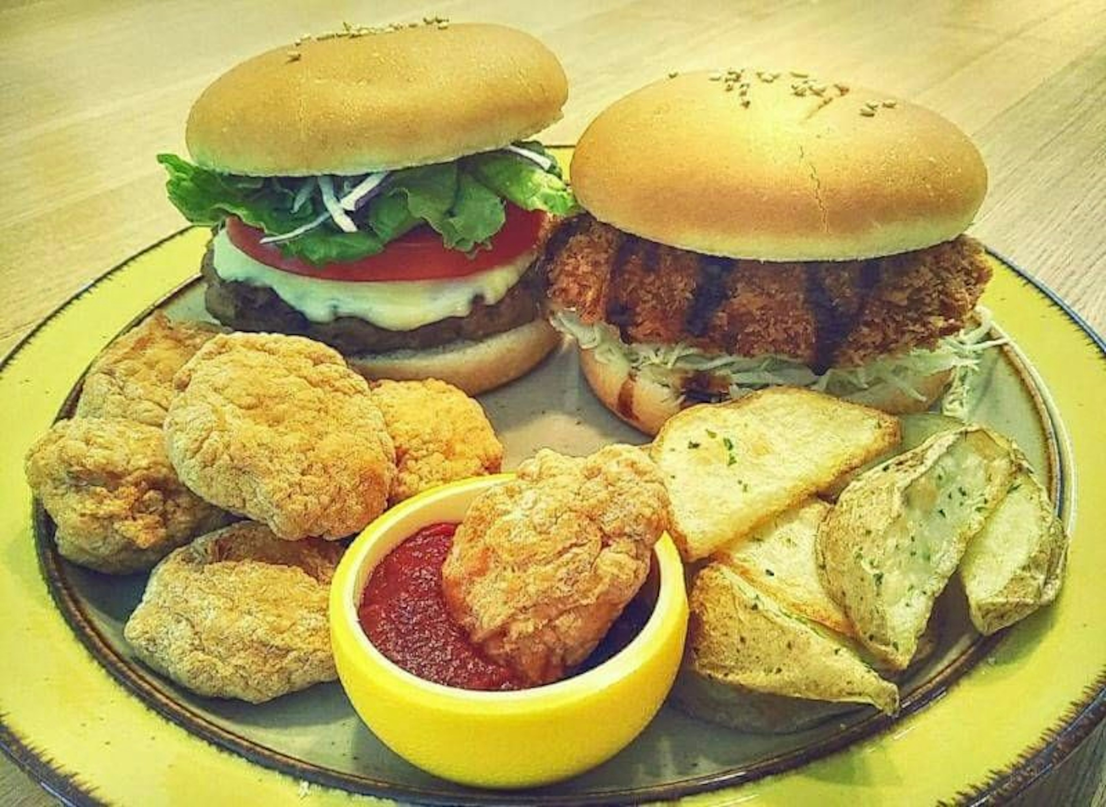 A plate featuring two burgers and a side of chicken nuggets and potato wedges