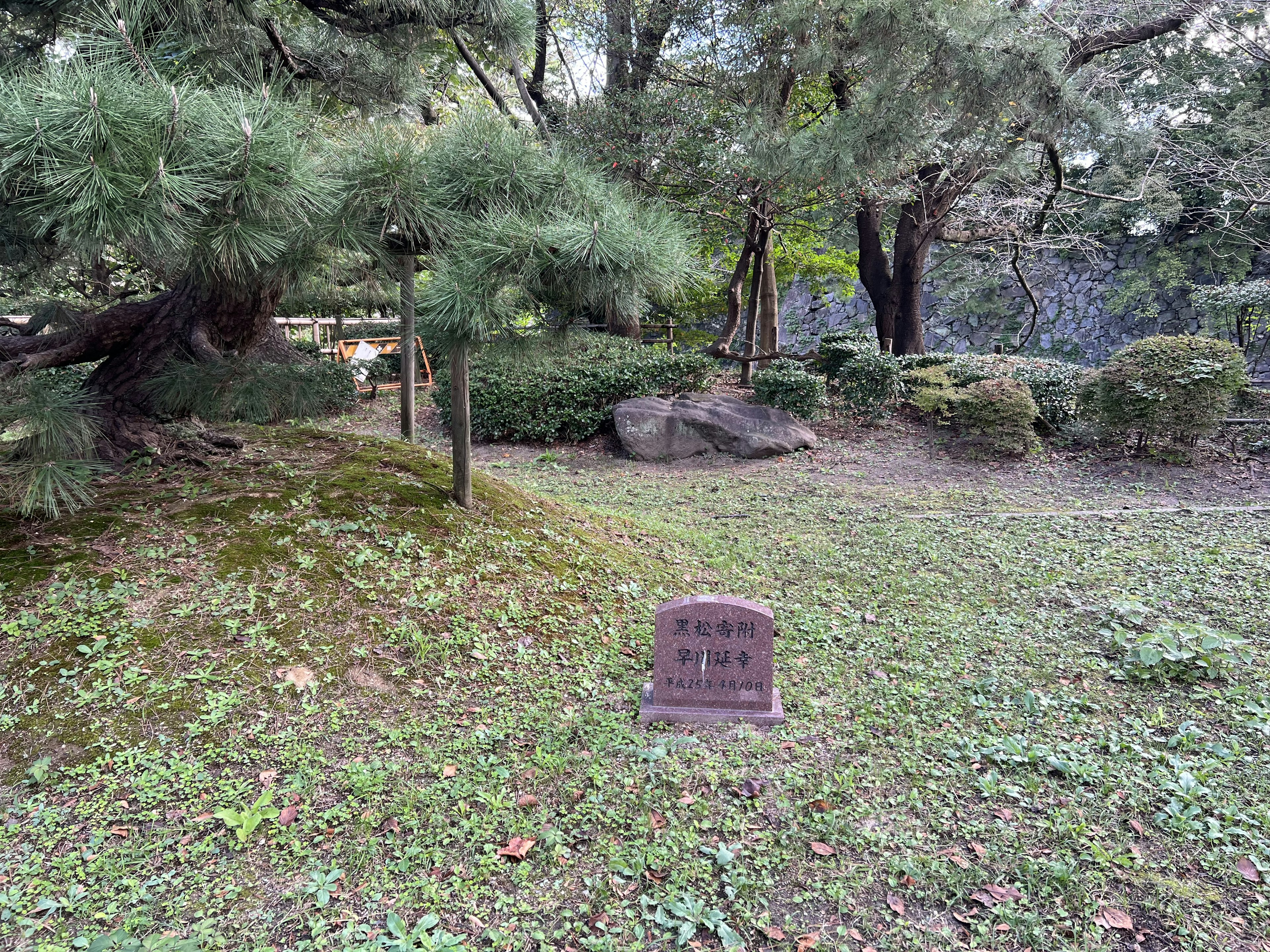 Stone monument in a lush garden surrounded by trees