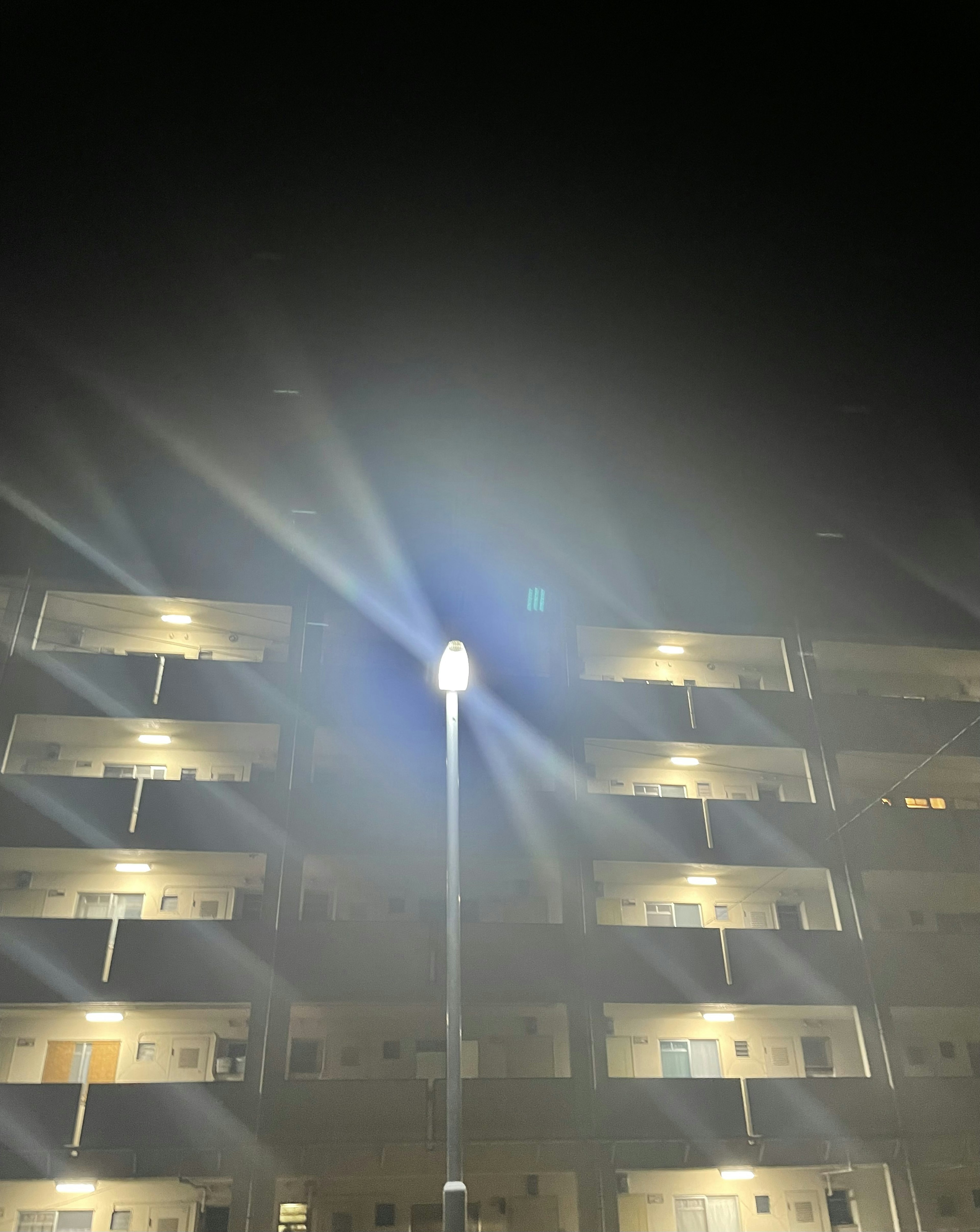 Farola iluminando un edificio de apartamentos en una noche brumosa