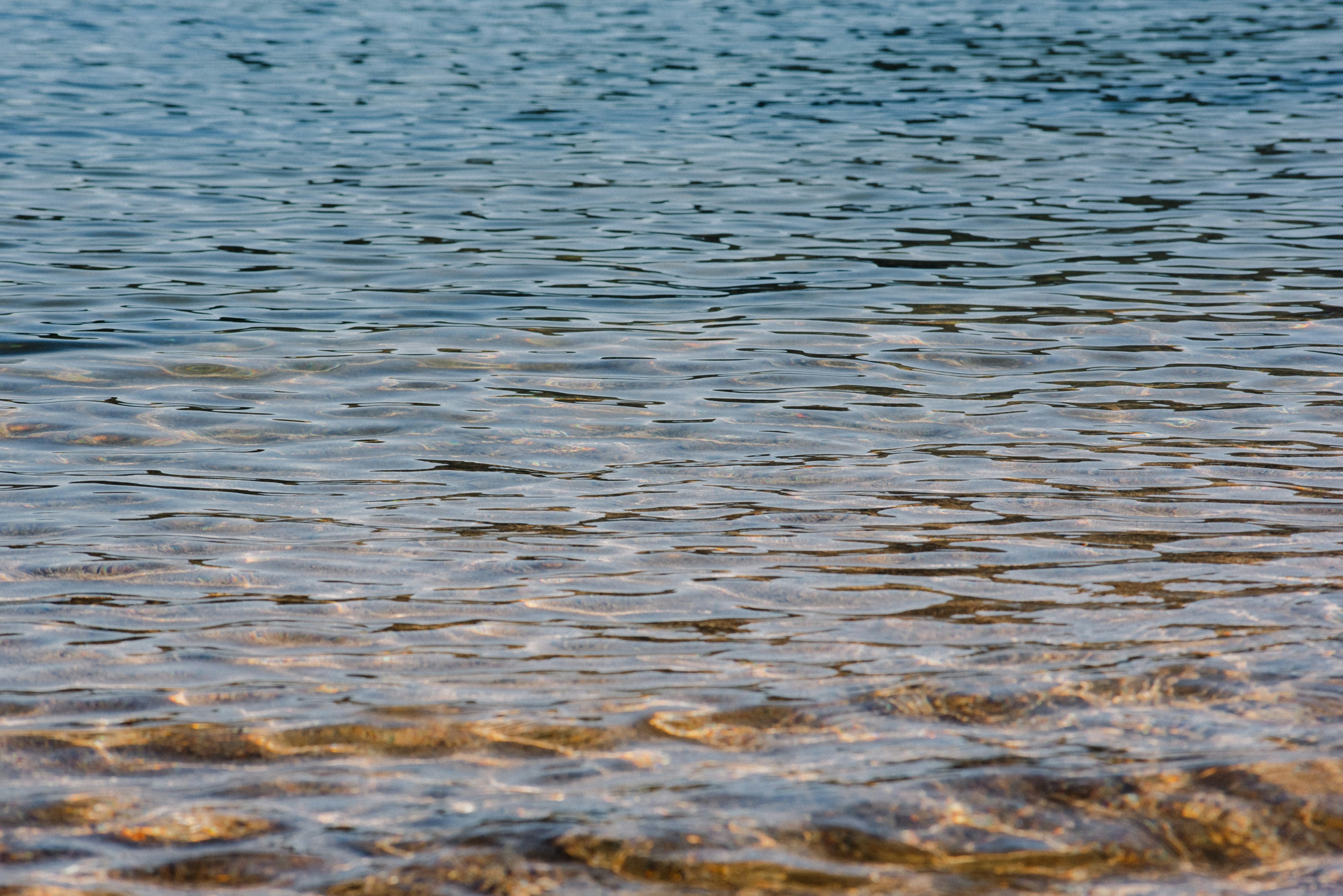 Klare Wasseroberfläche, die den blauen Himmel und sanfte Wellen reflektiert