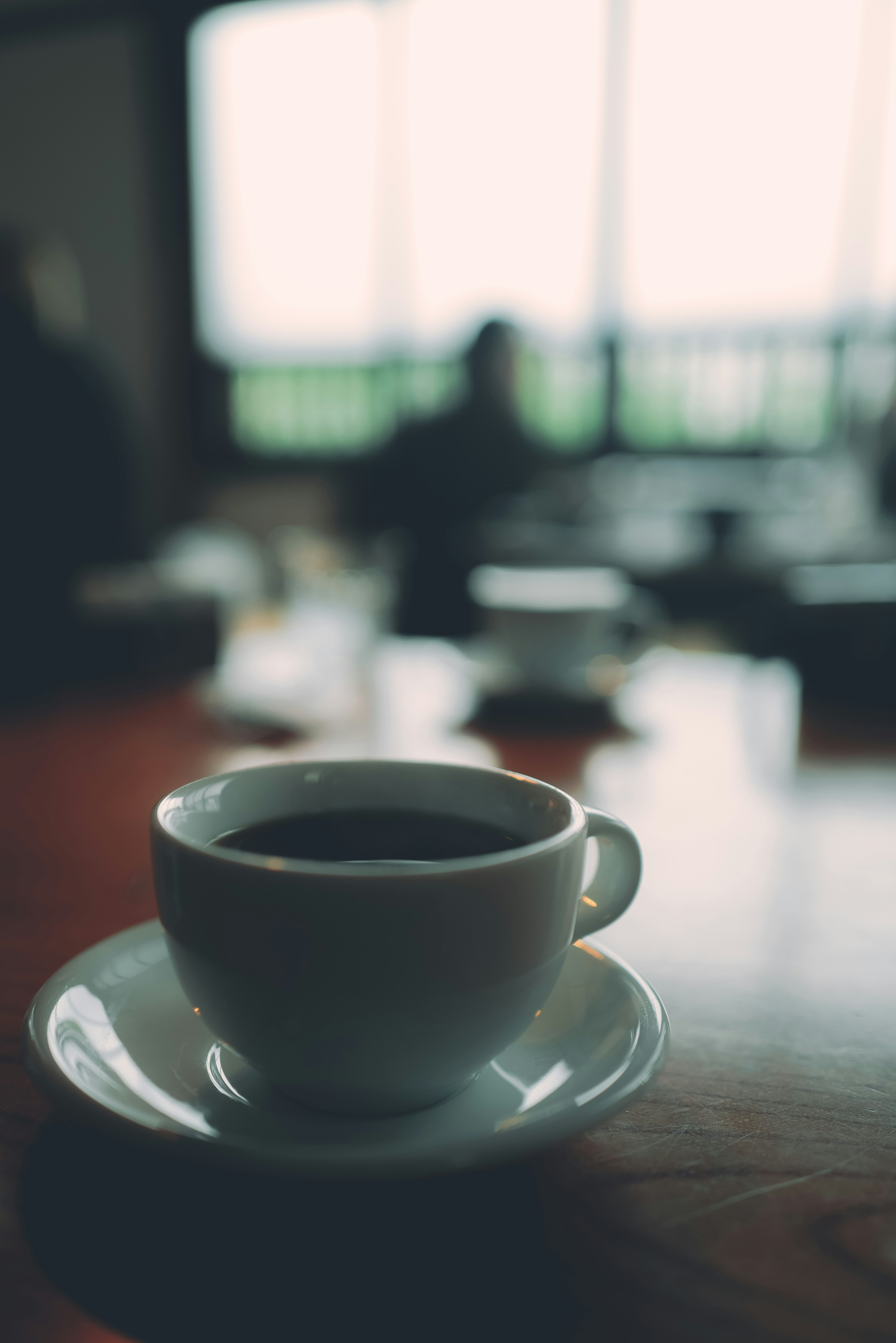 A coffee cup and saucer placed on a table in a cafe setting with a blurred background