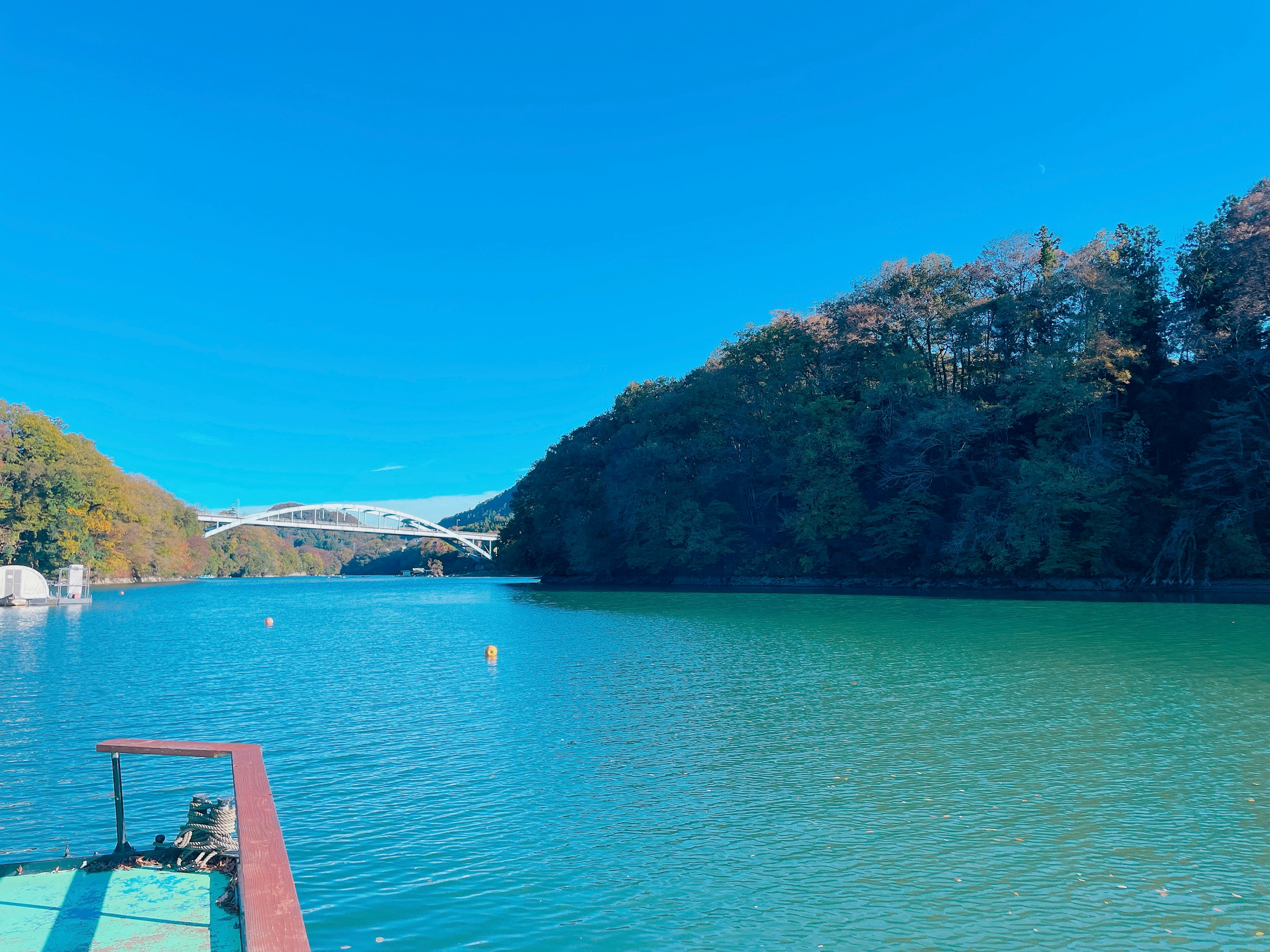 青い空と穏やかな水面が広がる川の風景 船の一部が視界に入る