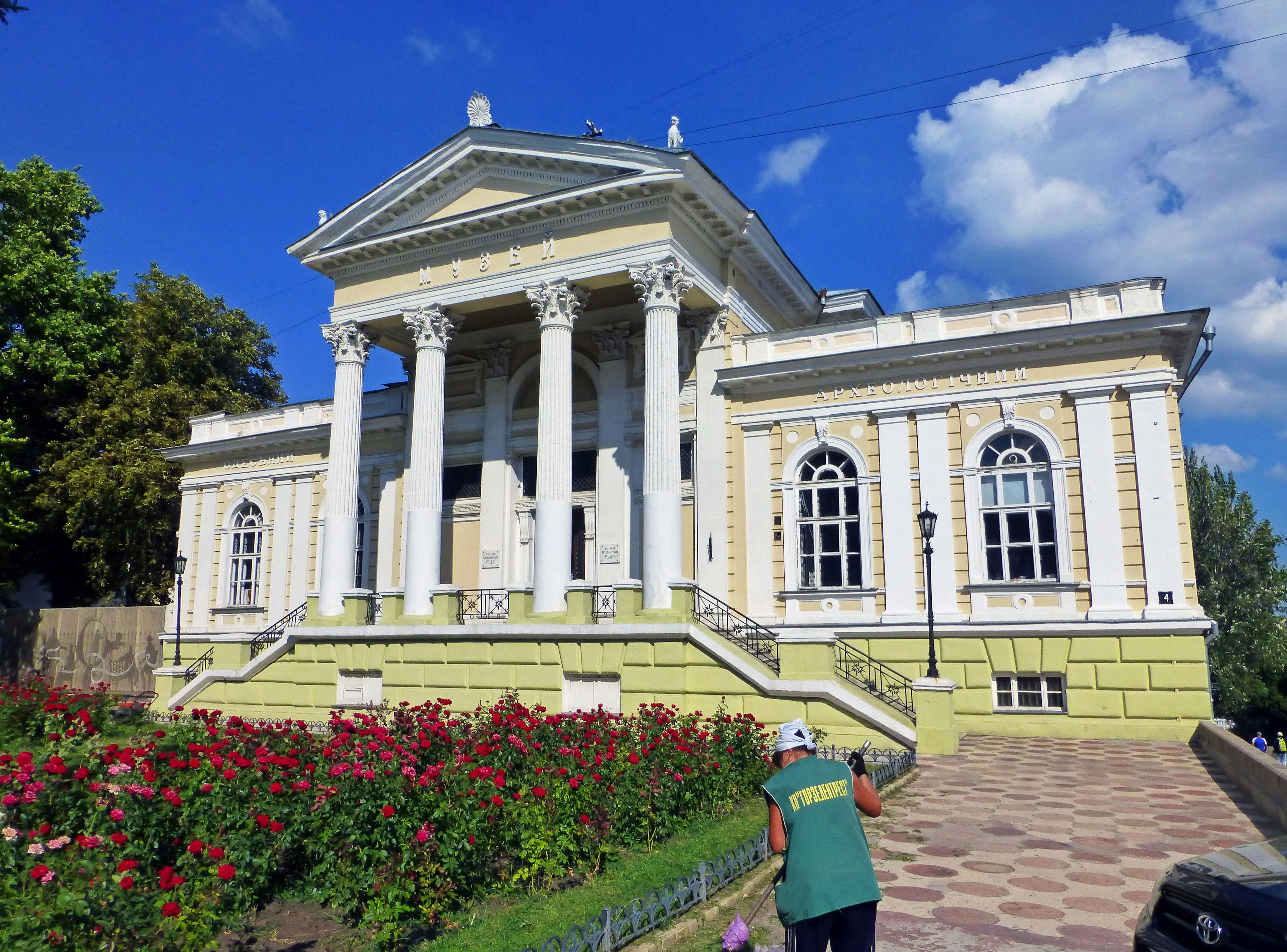 Edificio histórico con columnas rodeado de un jardín colorido