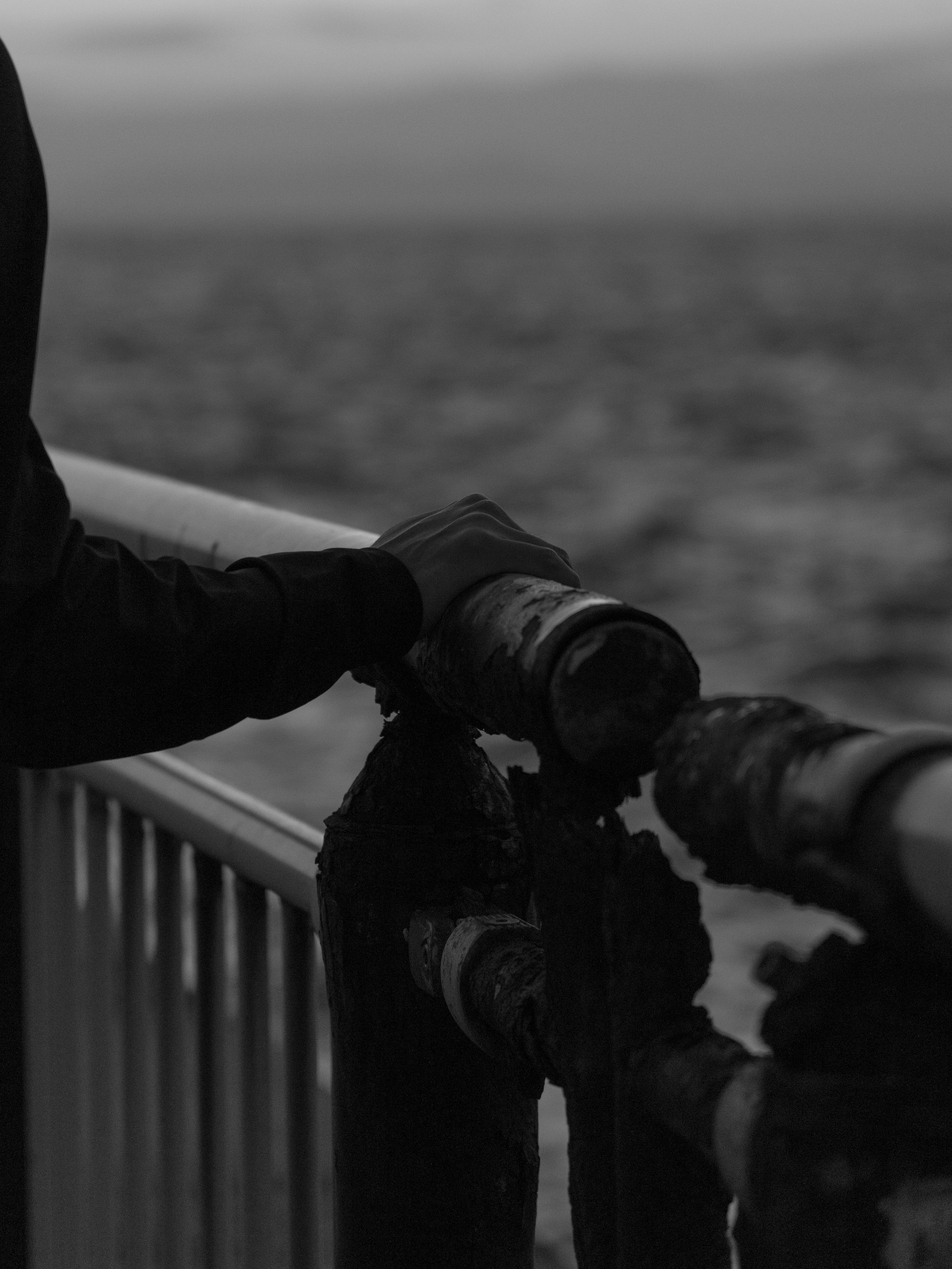 Monochrome image of a person reaching out towards the sea