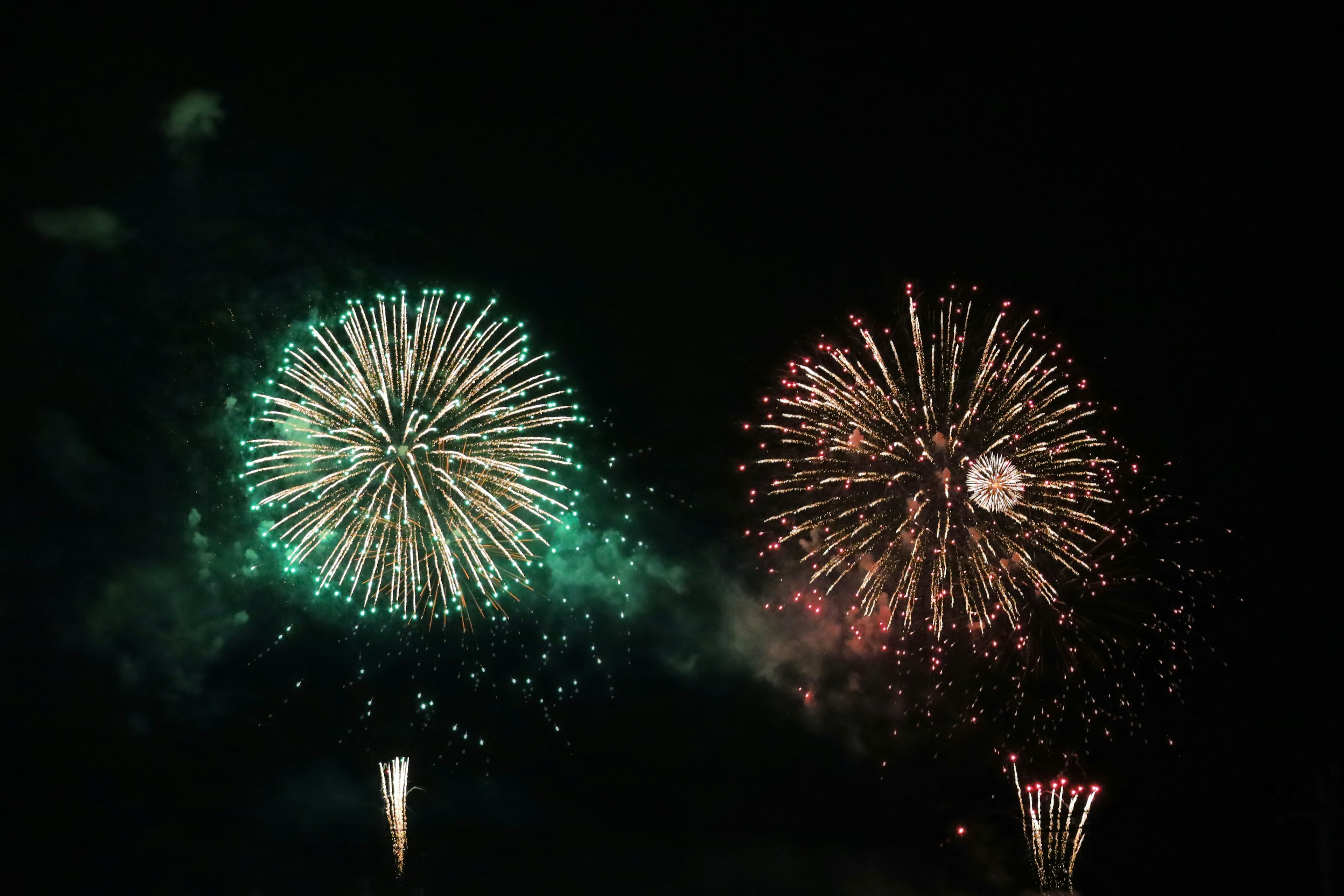 Una escena de fuegos artificiales vibrantes verdes y rojos estallando en el cielo nocturno