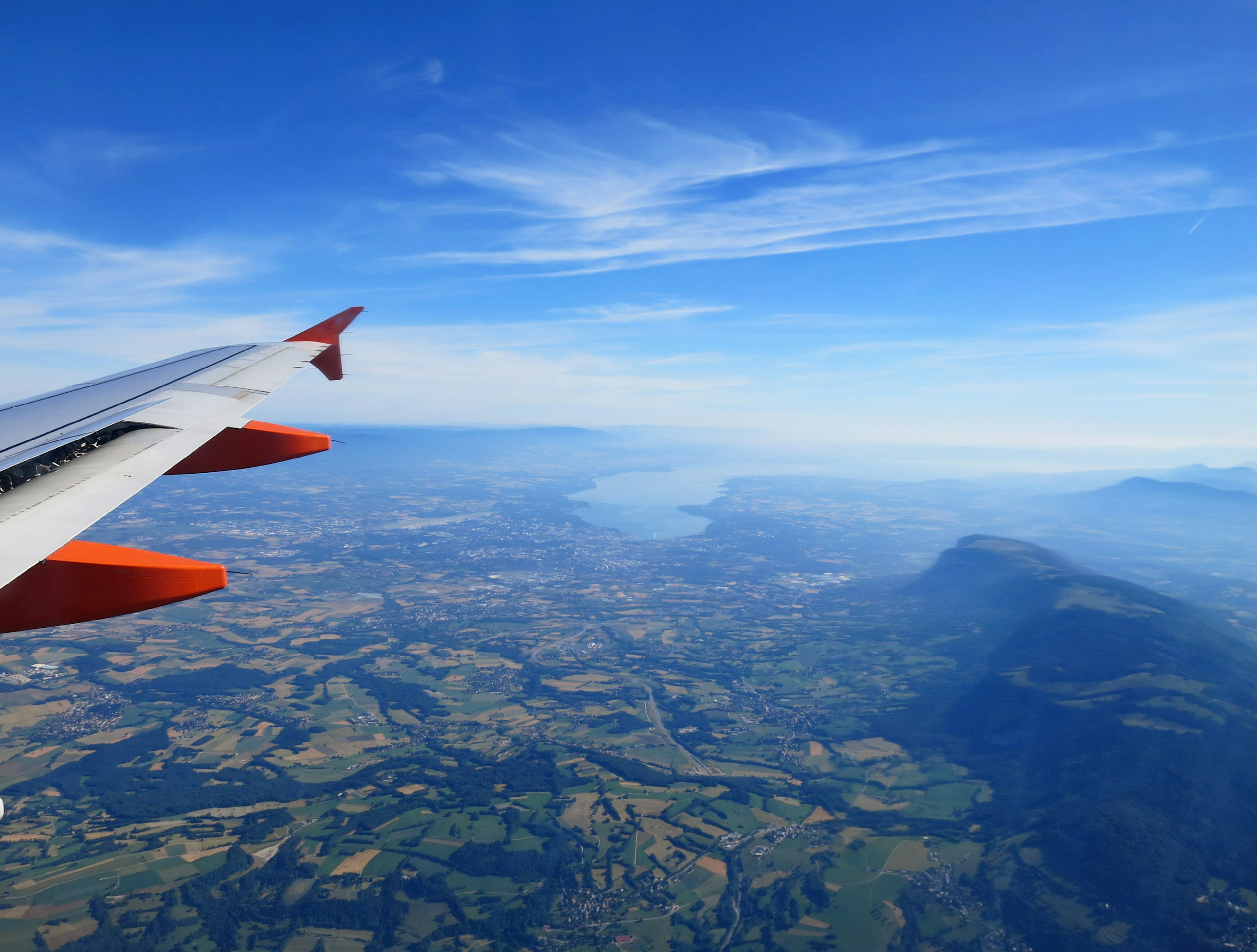 Flugzeugflügel vor dem Hintergrund eines blauen Himmels und einer weiten Landschaft