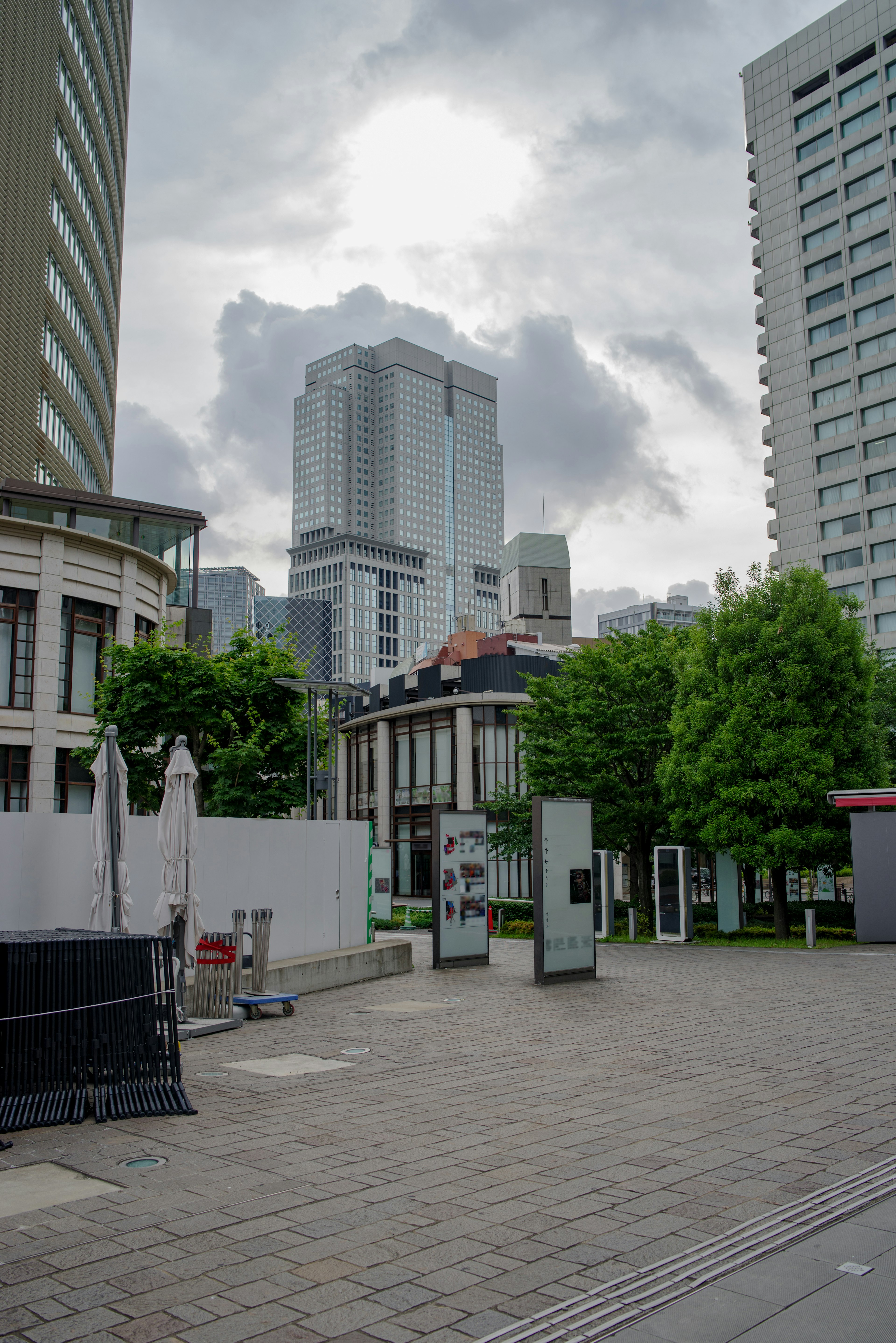 Pemandangan kota dengan gedung pencakar langit dan taman di bawah langit mendung