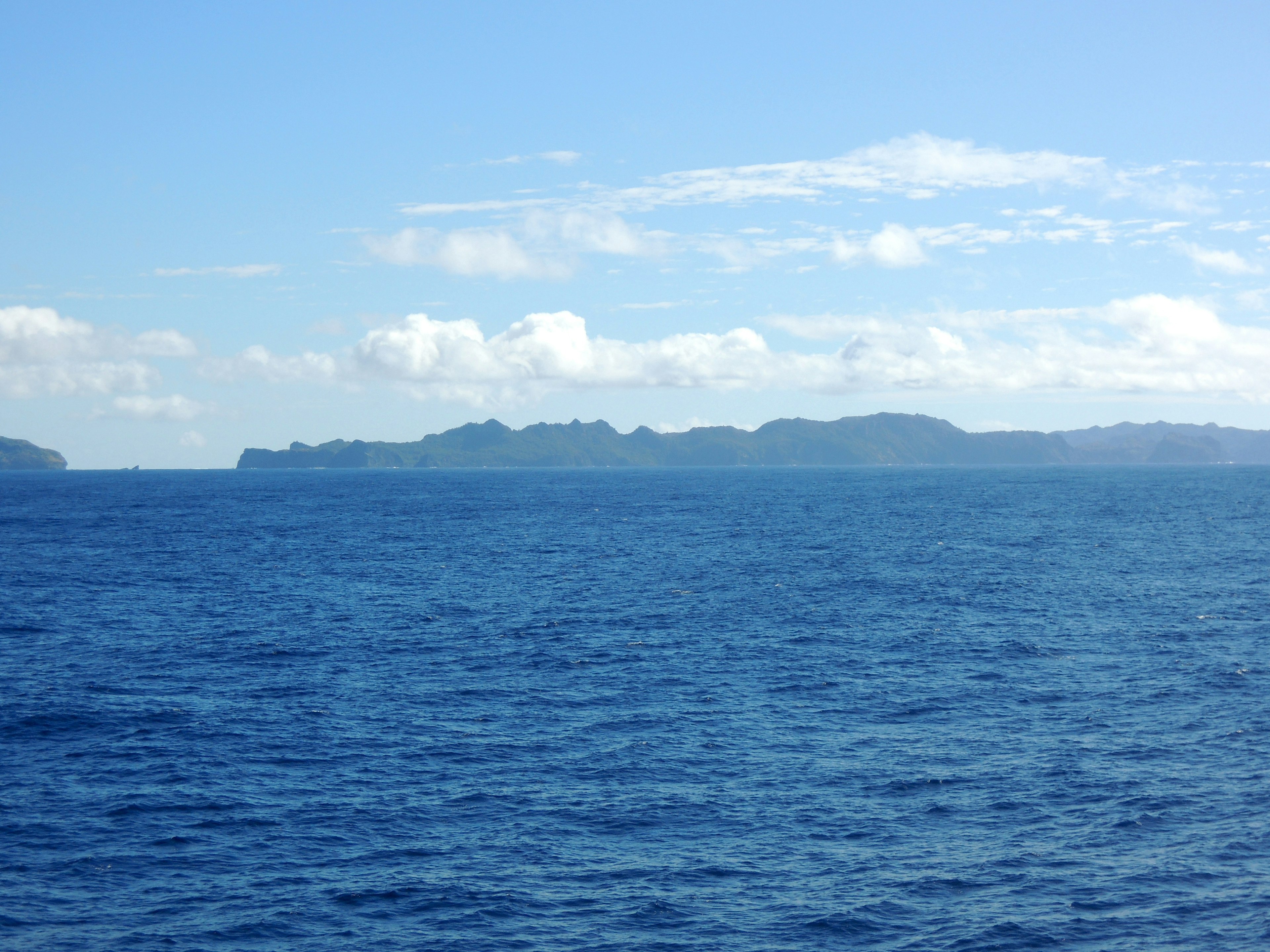 Blick auf den blauen Ozean mit fernen Inseln am Horizont