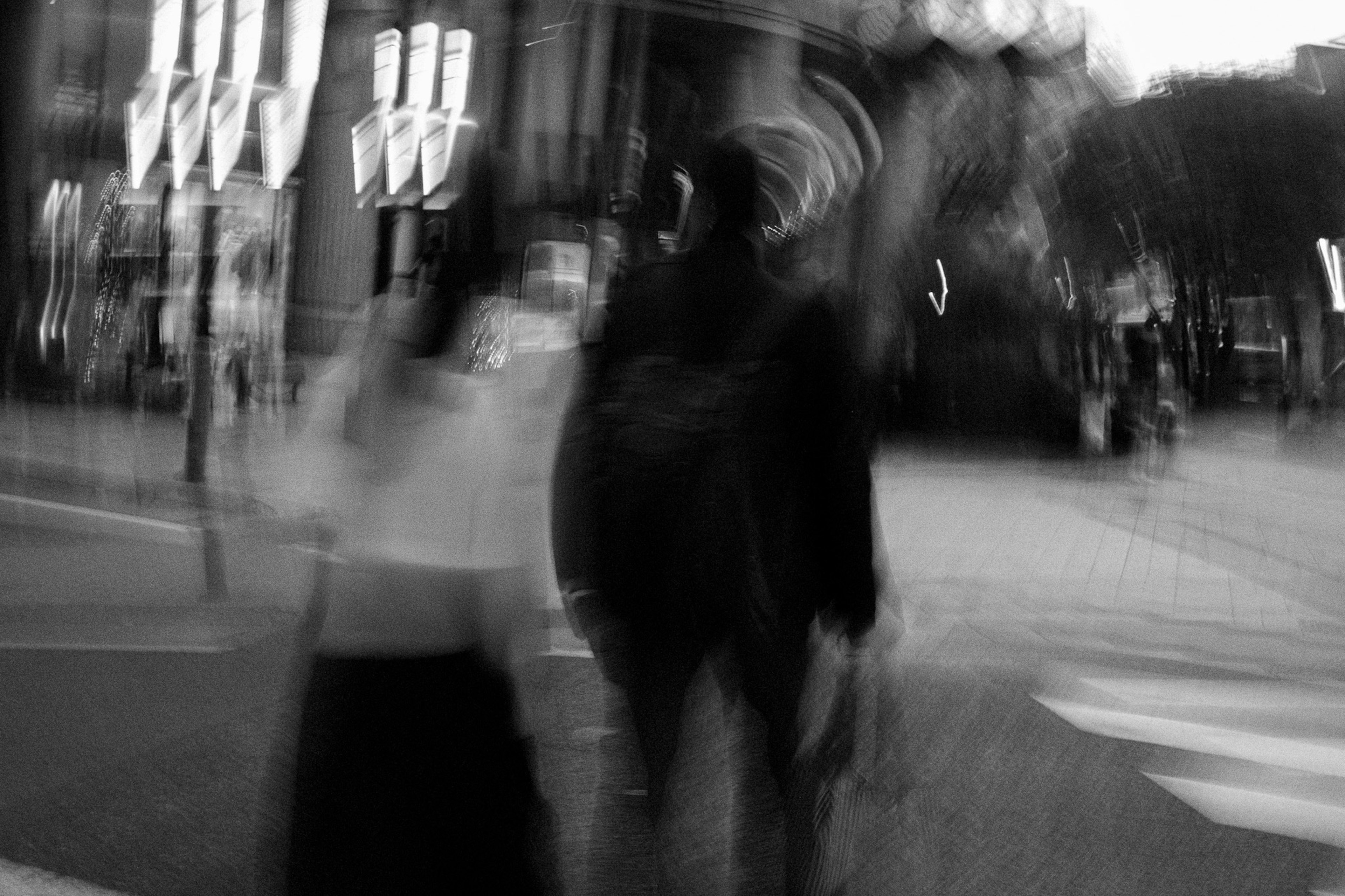 Two figures walking in a blurred urban setting with city lights