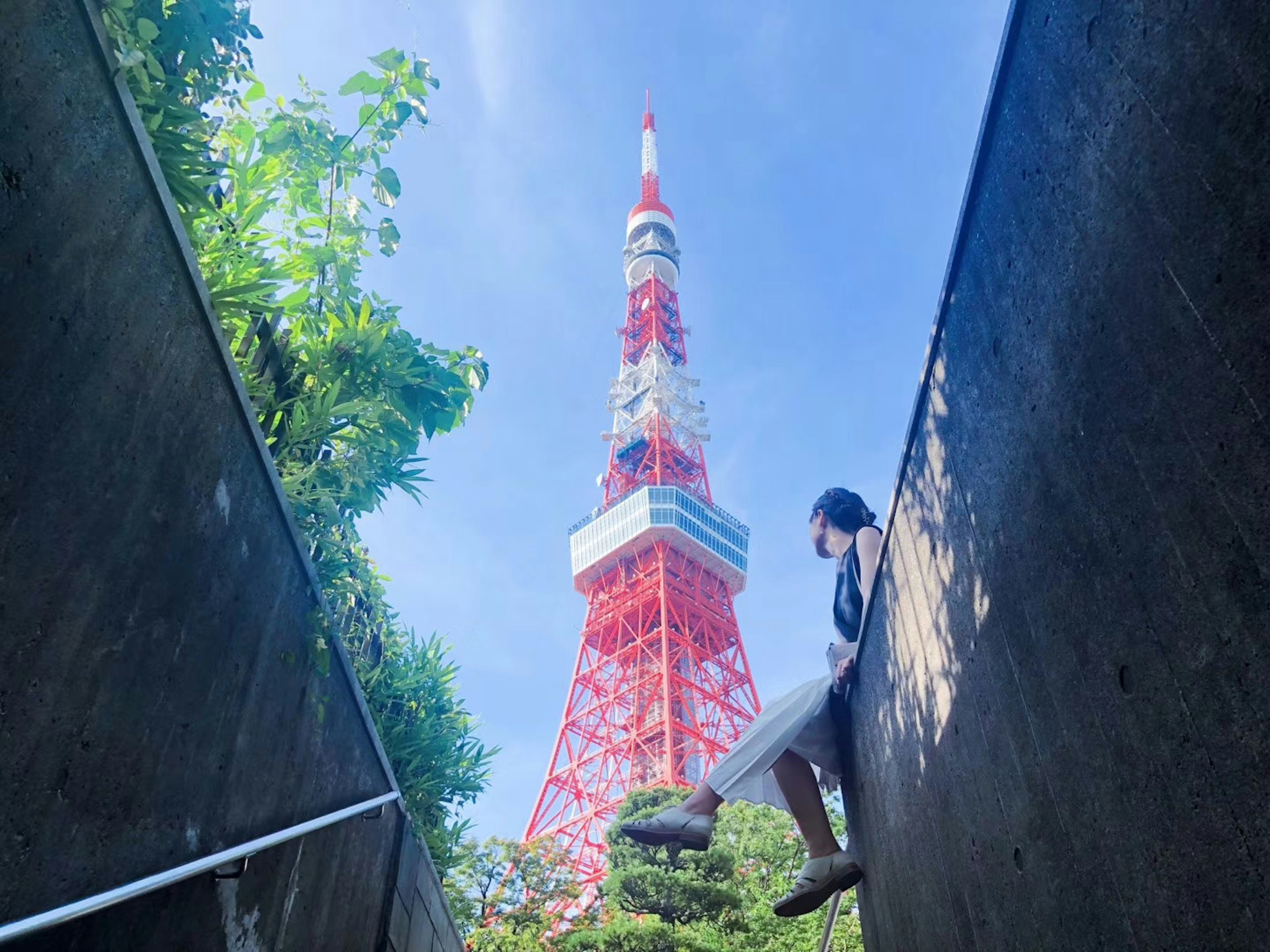 Person, die in einer grünen Umgebung sitzt, mit dem Tokyo Tower im Hintergrund