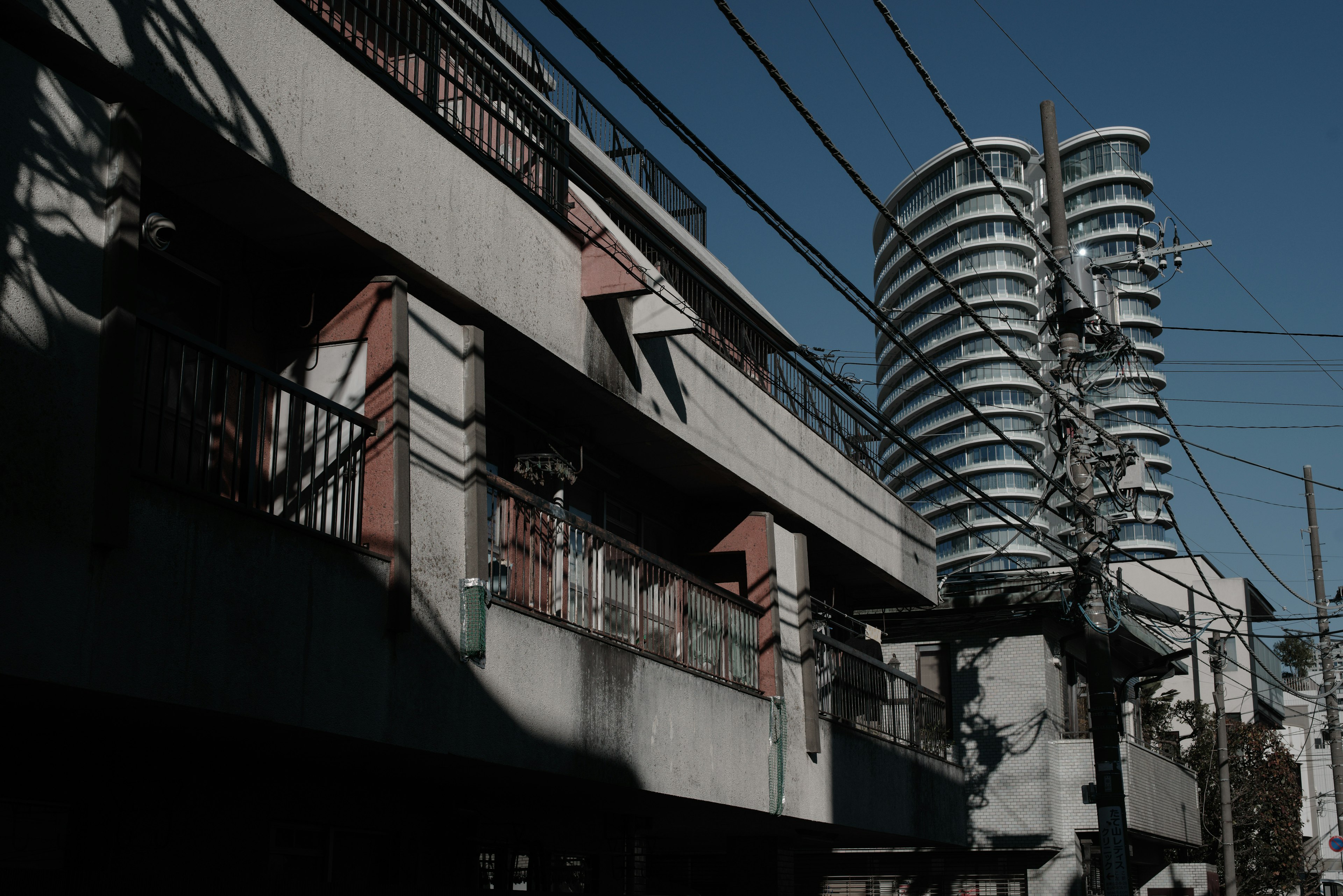 Urban landscape featuring a modern high-rise building alongside older structures and power lines