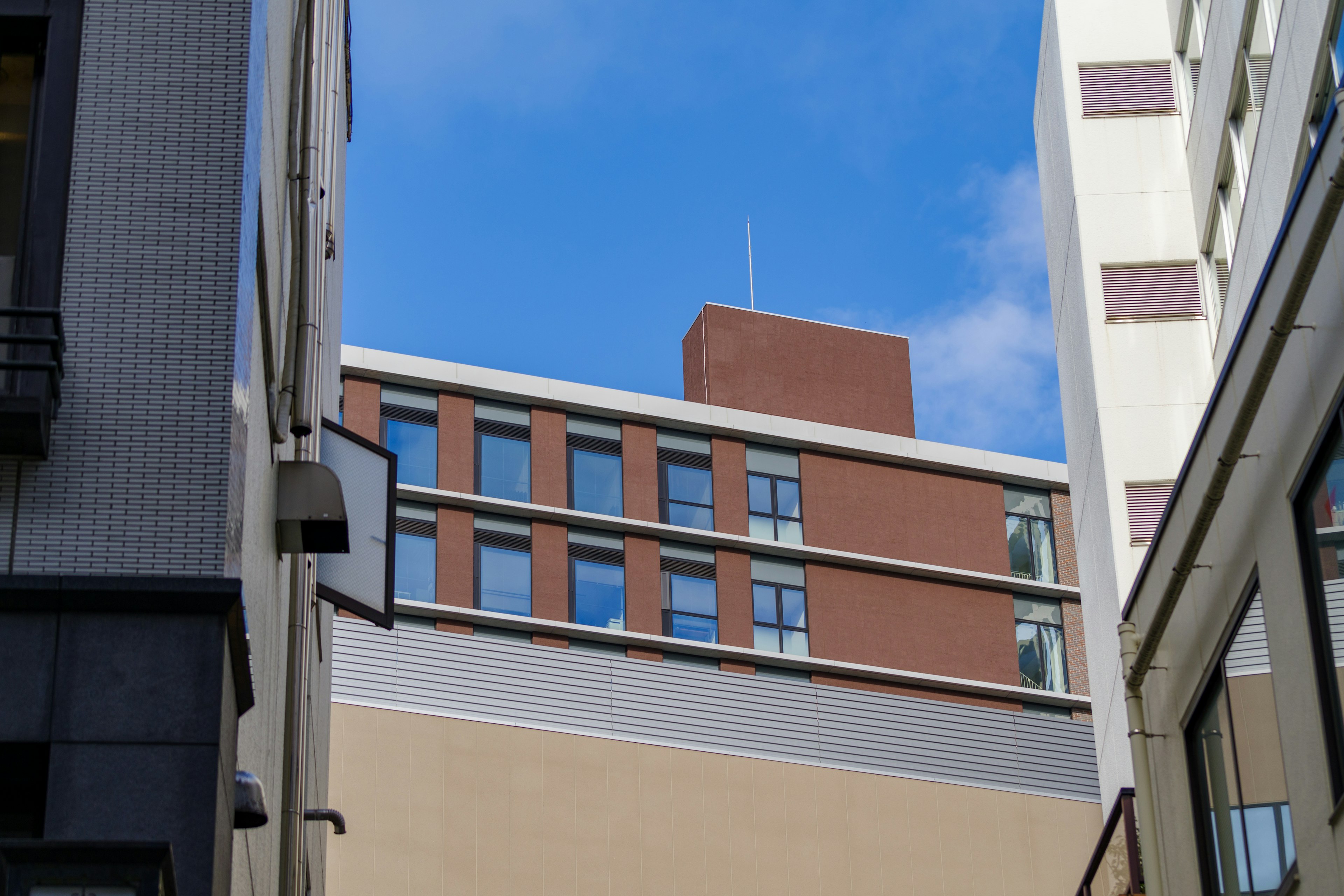 Narrow alley between modern buildings under a blue sky