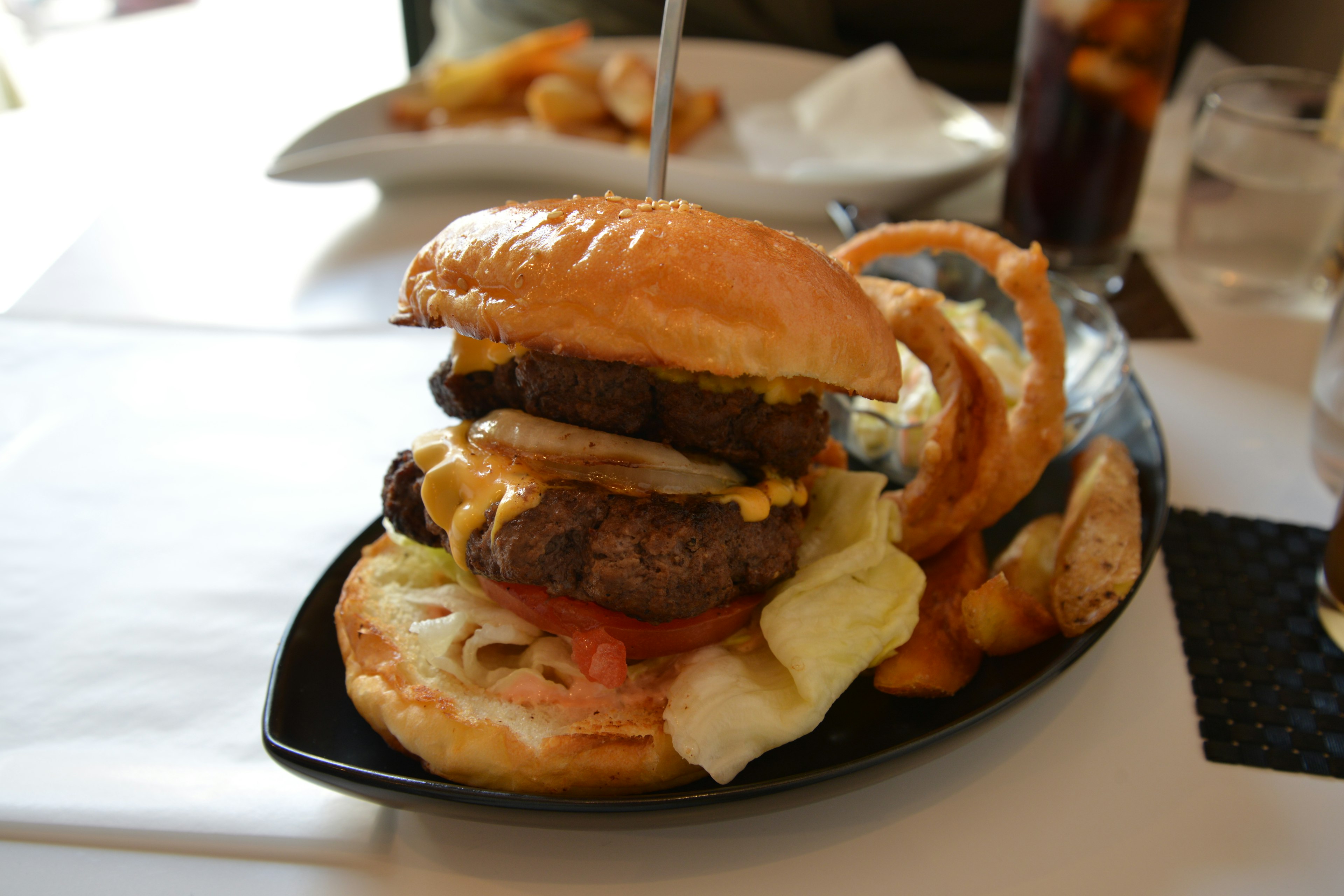 Hamburger succulento con formaggio e anelli di cipolla su un piatto