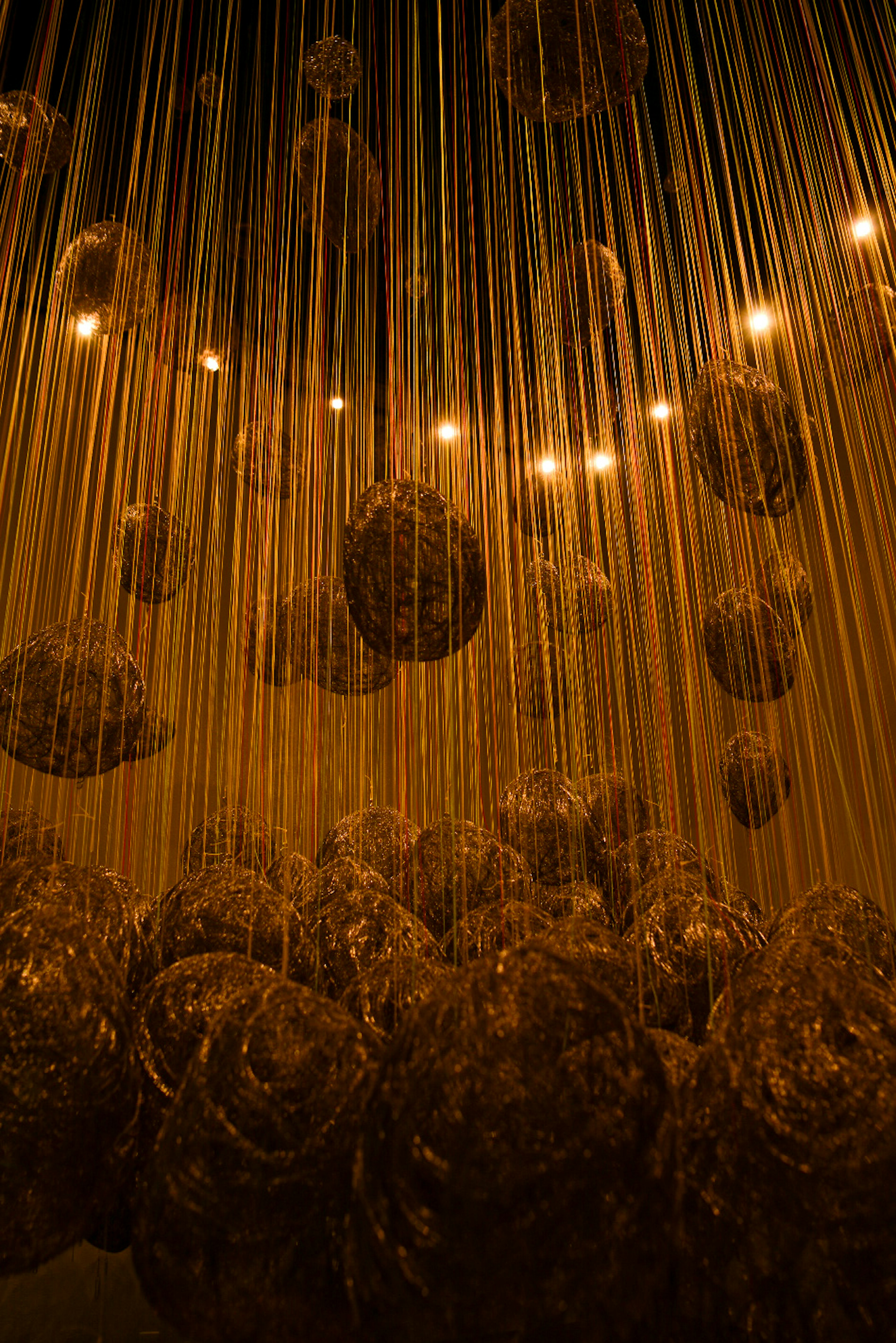 Art installation featuring suspended glowing objects in a dimly lit space