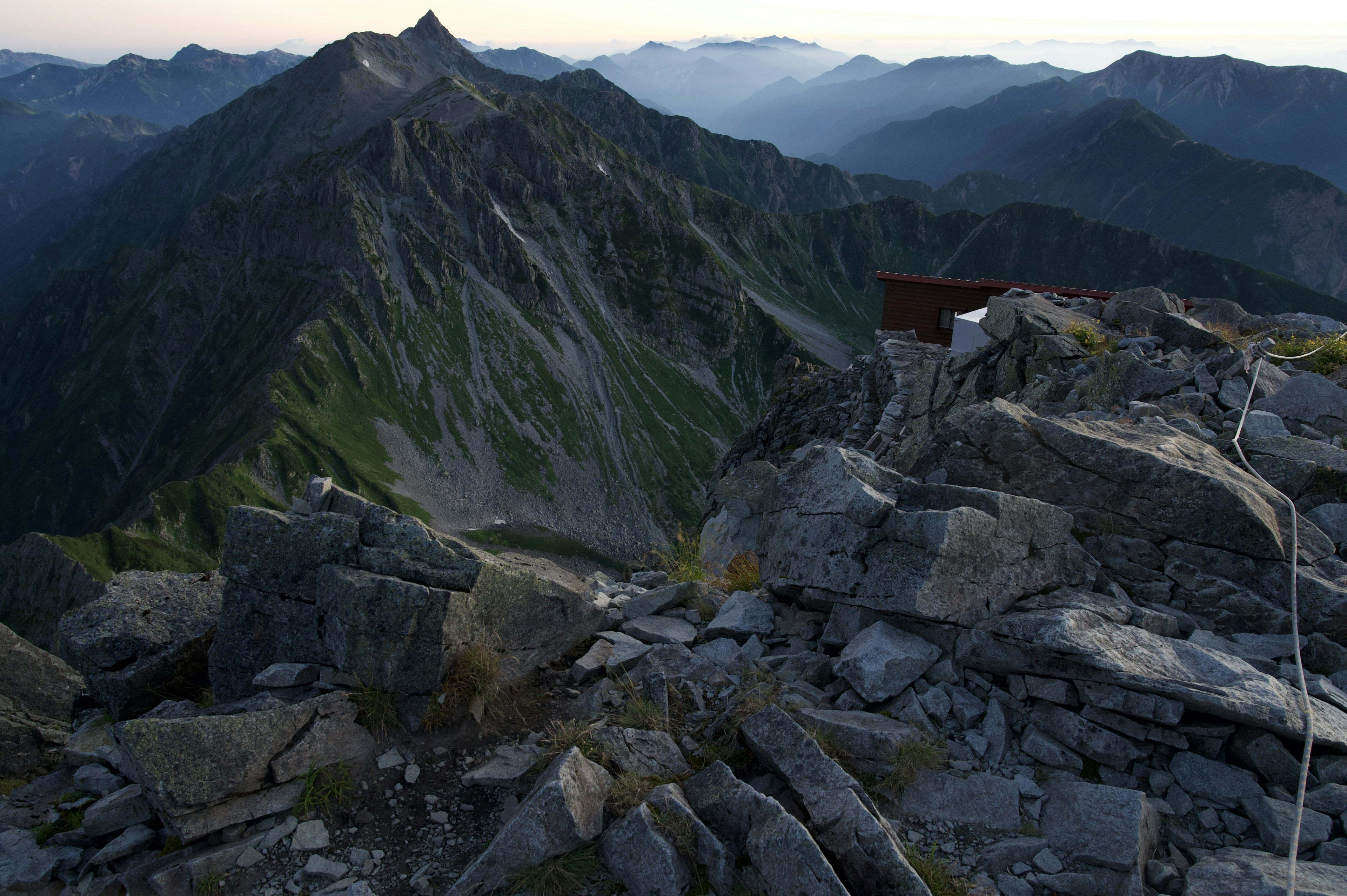 View from the mountain summit rocky terrain green slopes and distant mountains