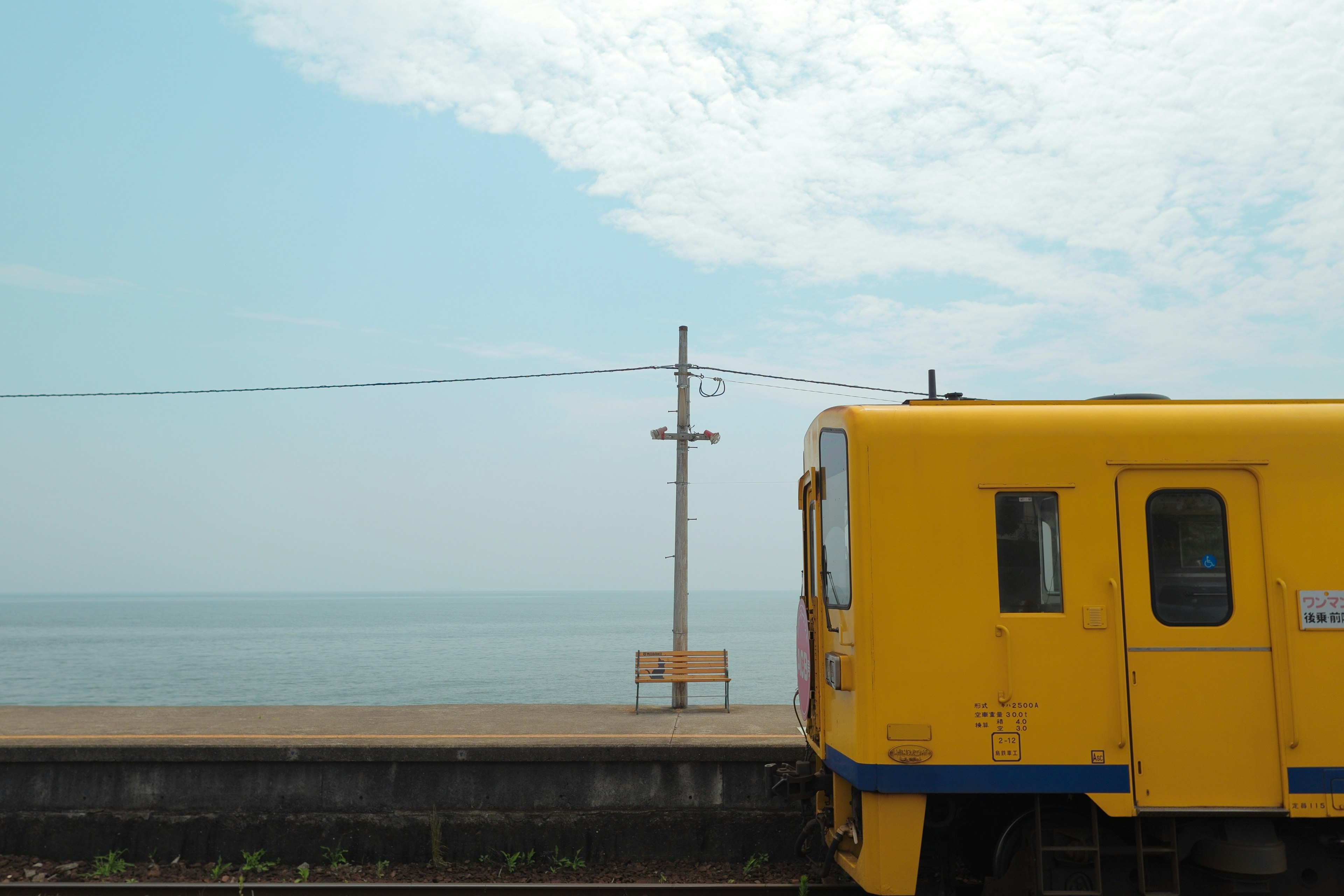 Kereta kuning dengan latar belakang laut dan tiang utilitas