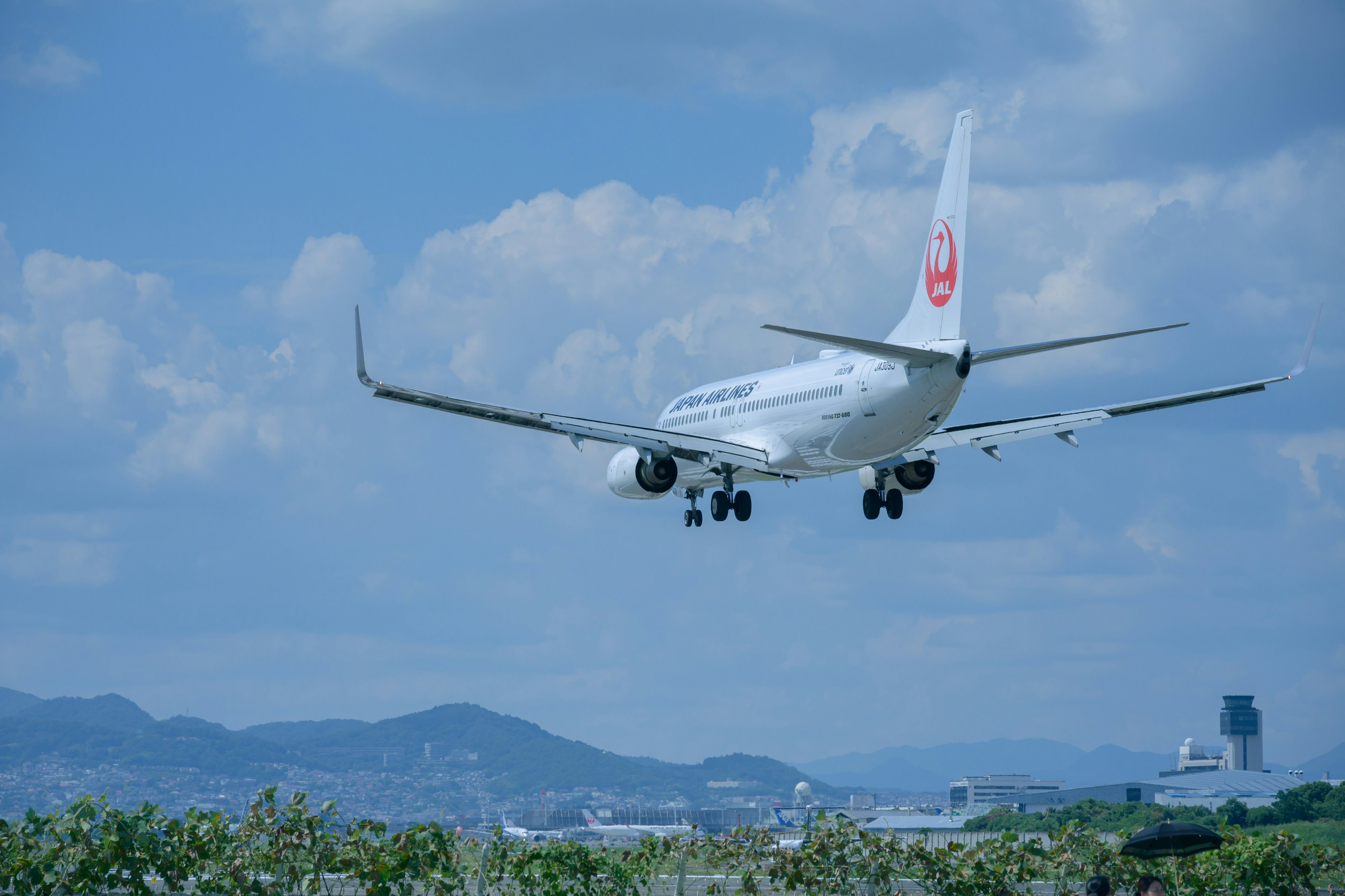 Airplane landing against a blue sky with clouds