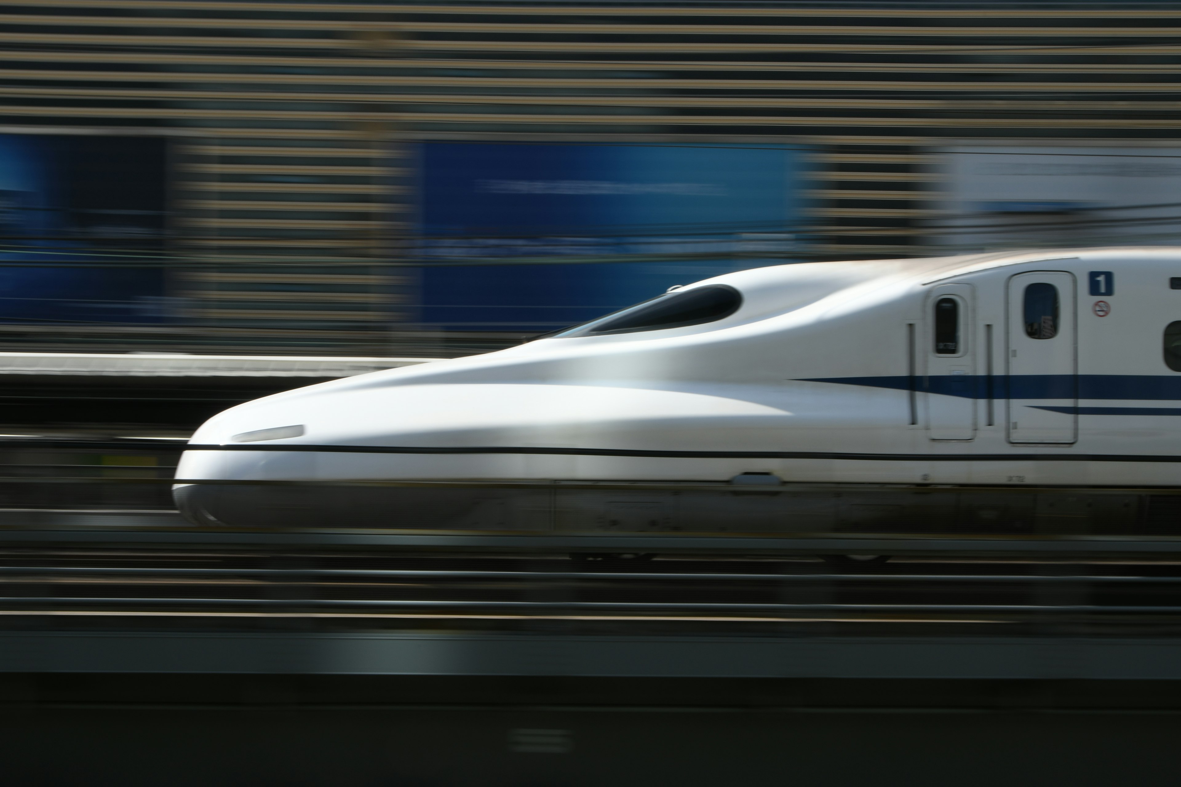 Shinkansen fährt schnell vorbei mit unscharfen Hintergrundschildern