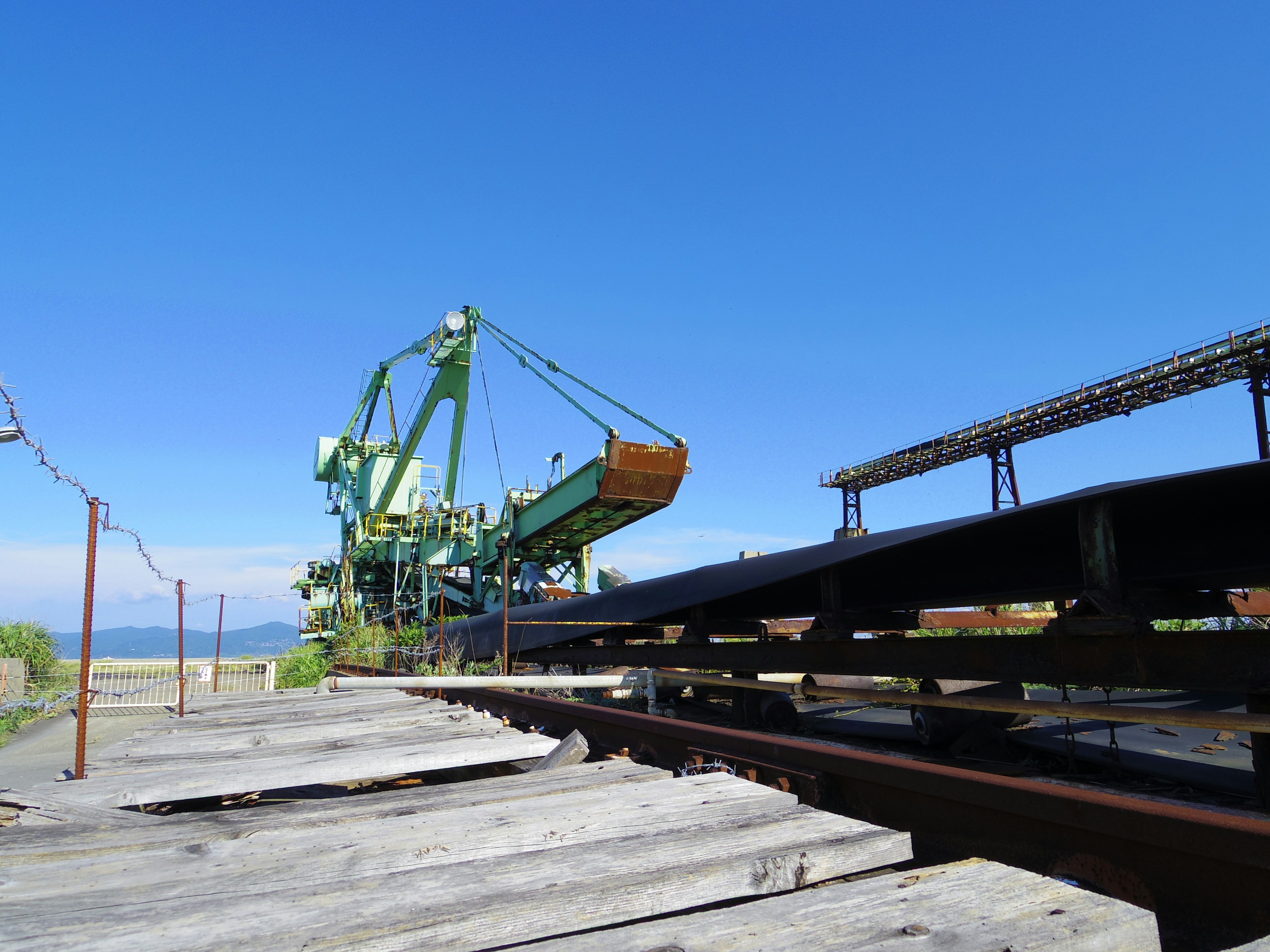 Grúa industrial cargando mercancías en vías de tren