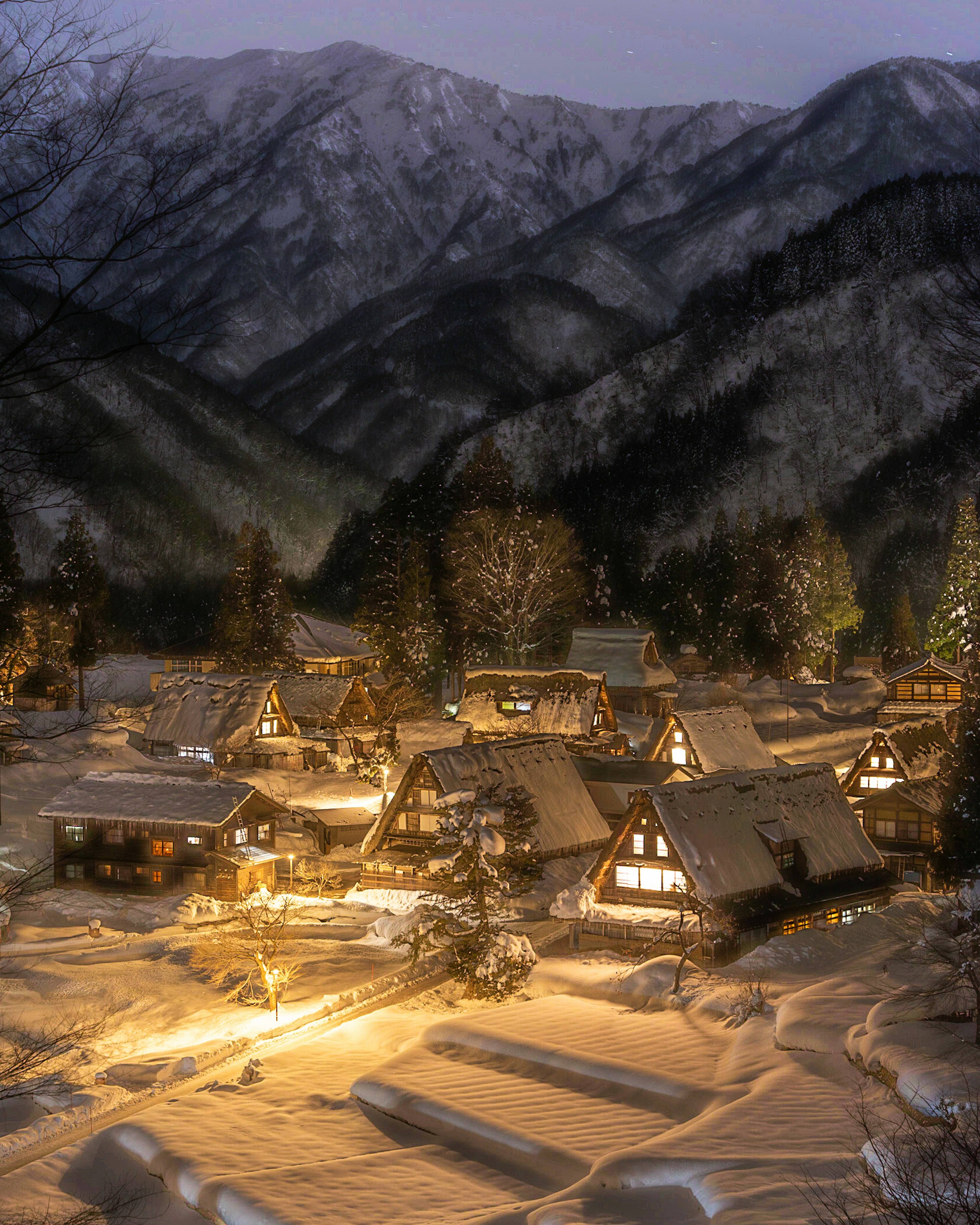 被雪覆盖的合掌造村的夜景，四周环绕着山脉