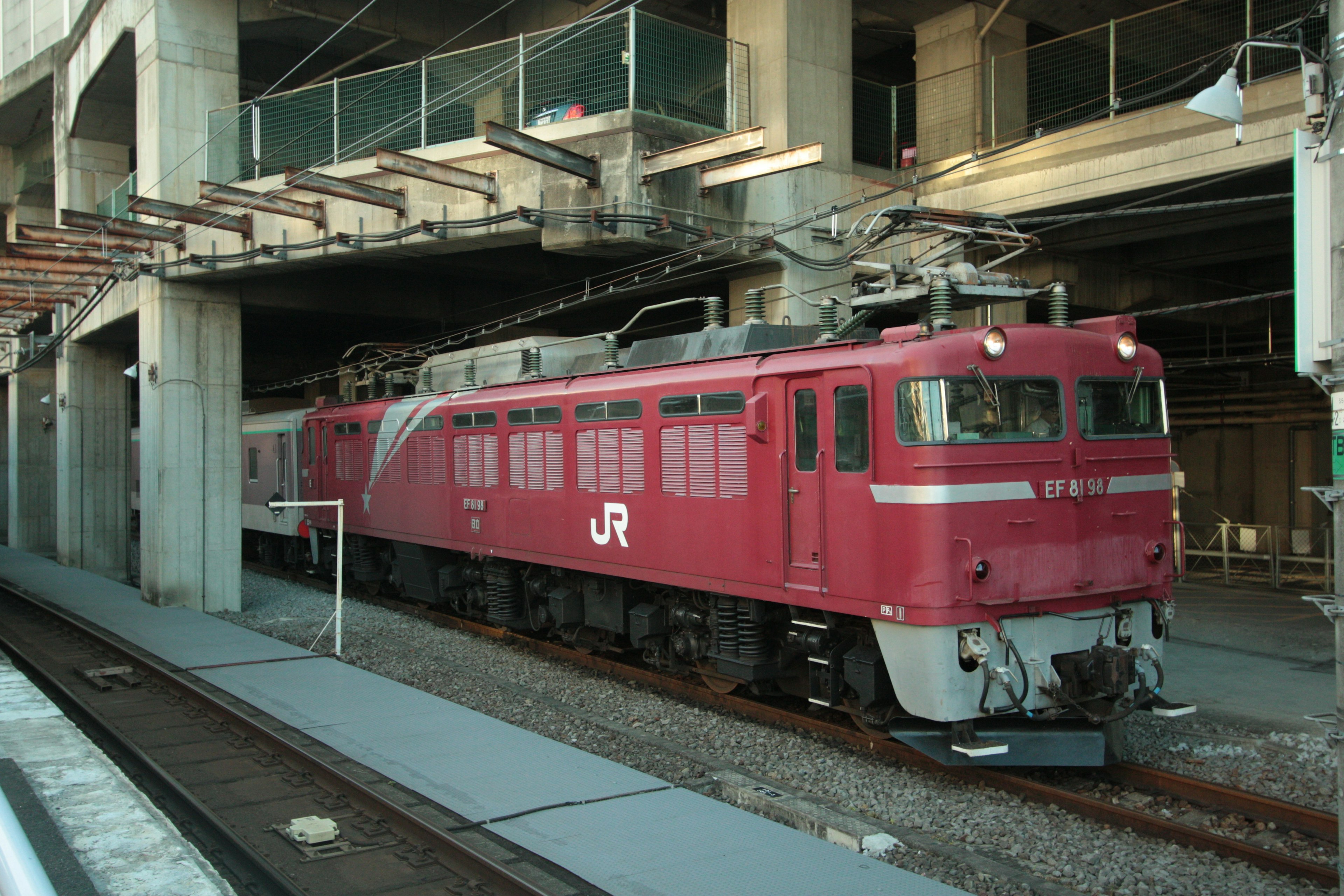 赤いJRの機関車が駅のプラットフォームに停車している