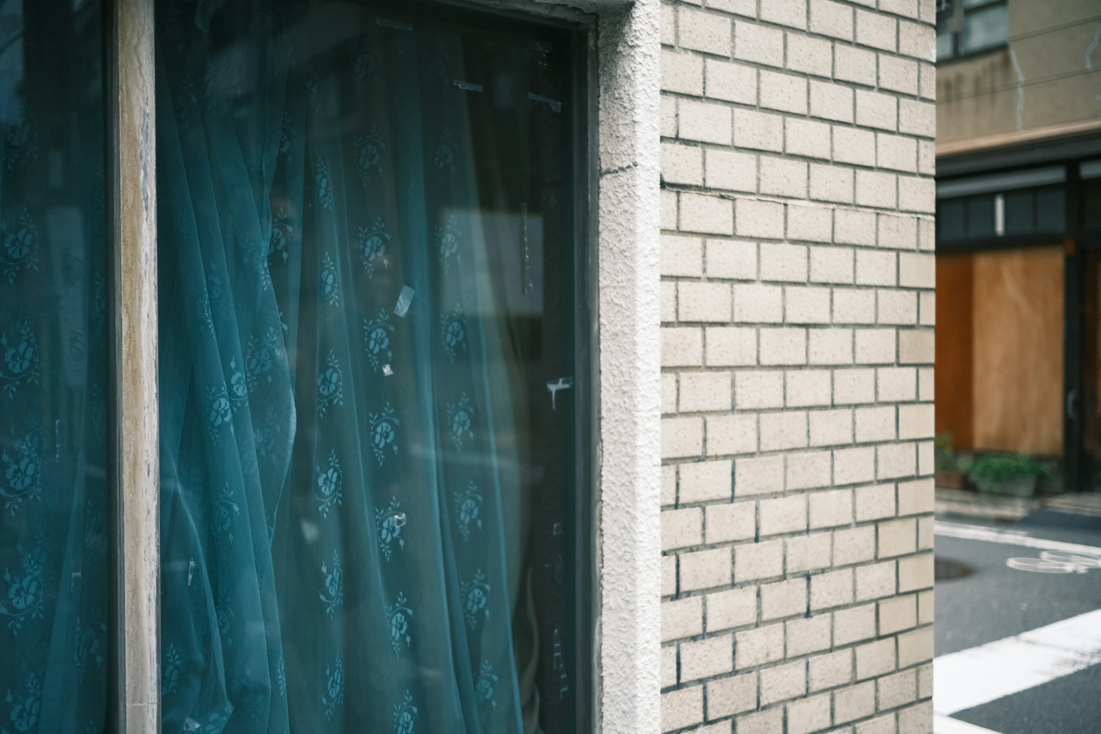 Window with blue curtains on a brick wall corner