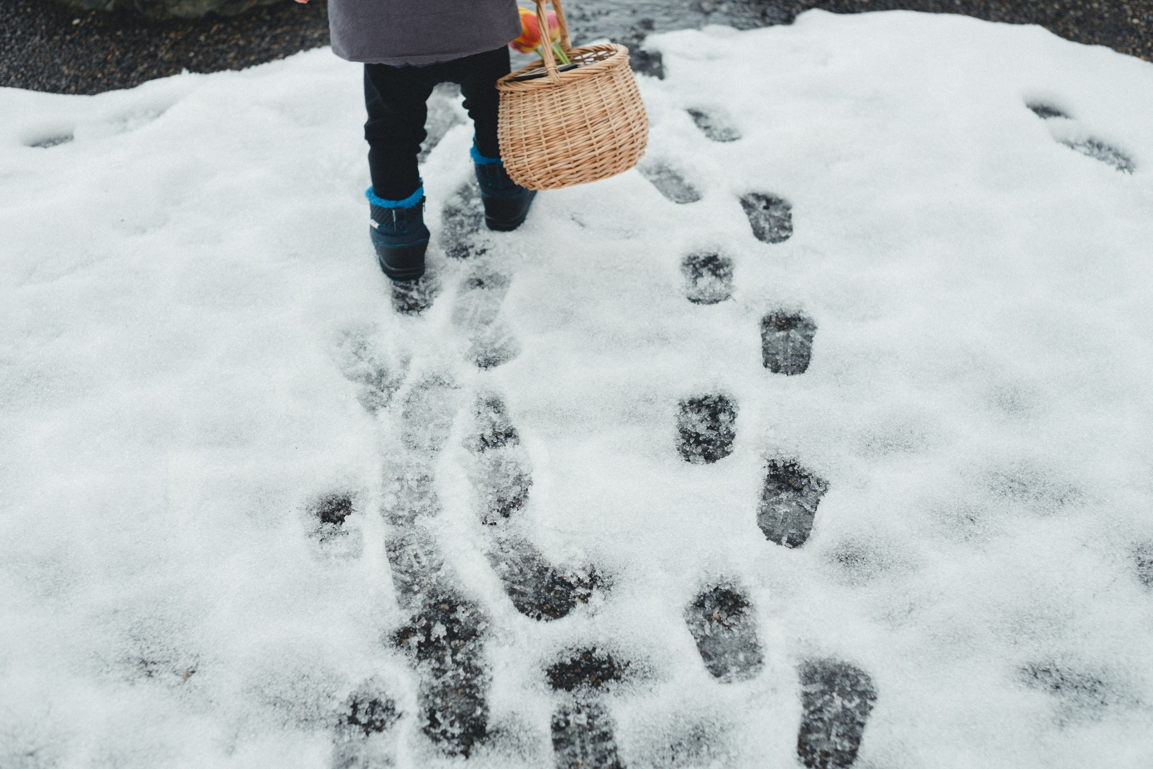 Enfant marchant dans la neige laissant des empreintes tout en tenant un panier