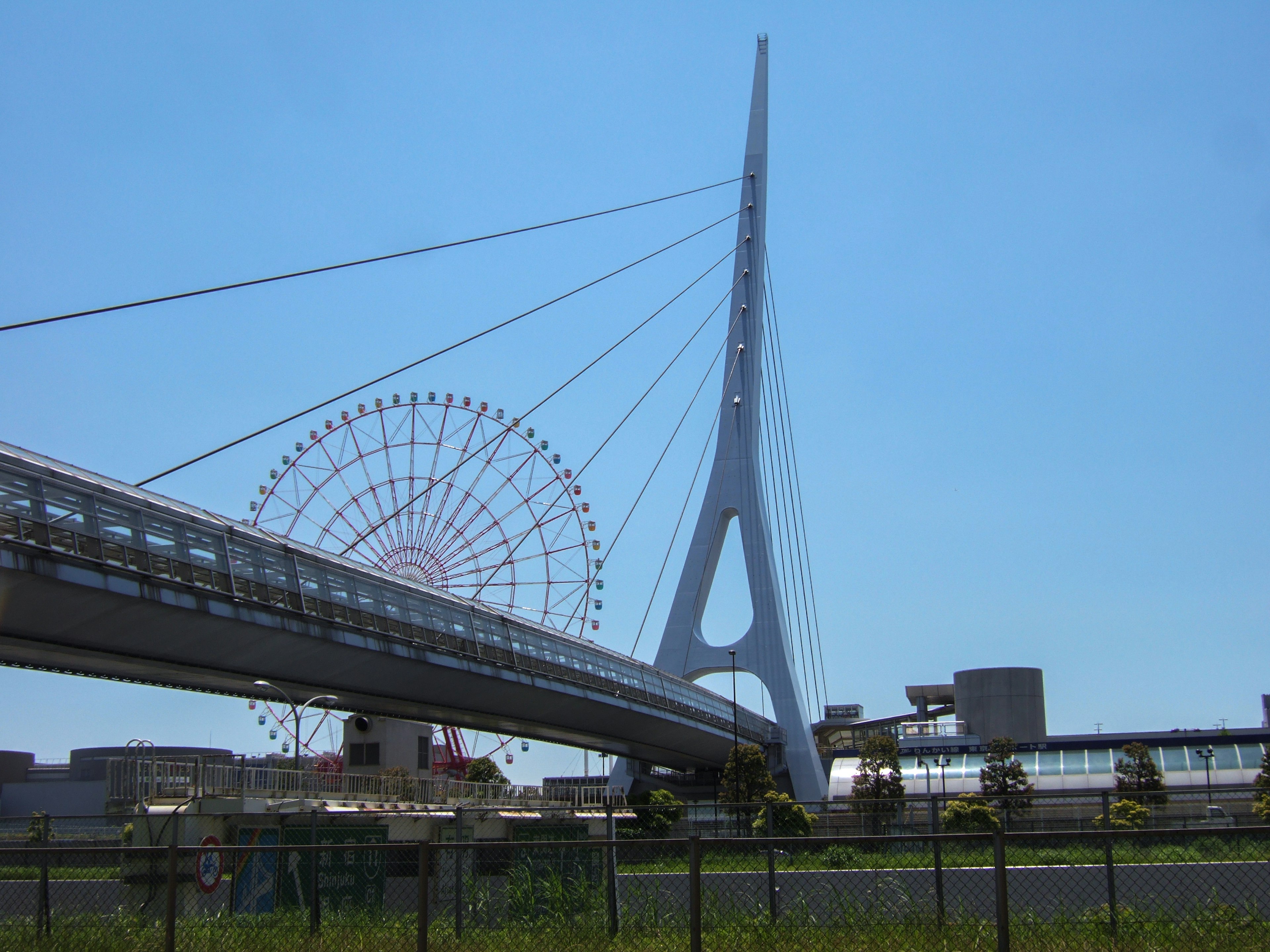 Vista de una gran noria y un puente moderno bajo un cielo azul