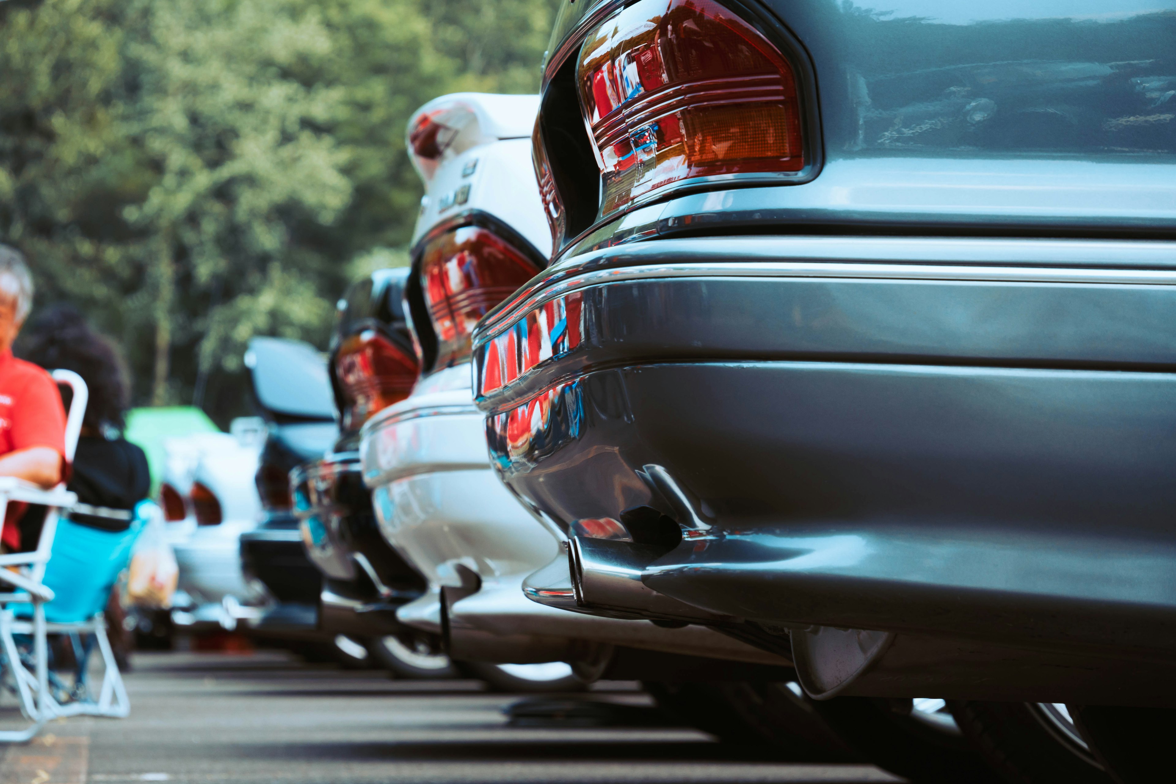 A row of car bumpers with blurred trees in the background