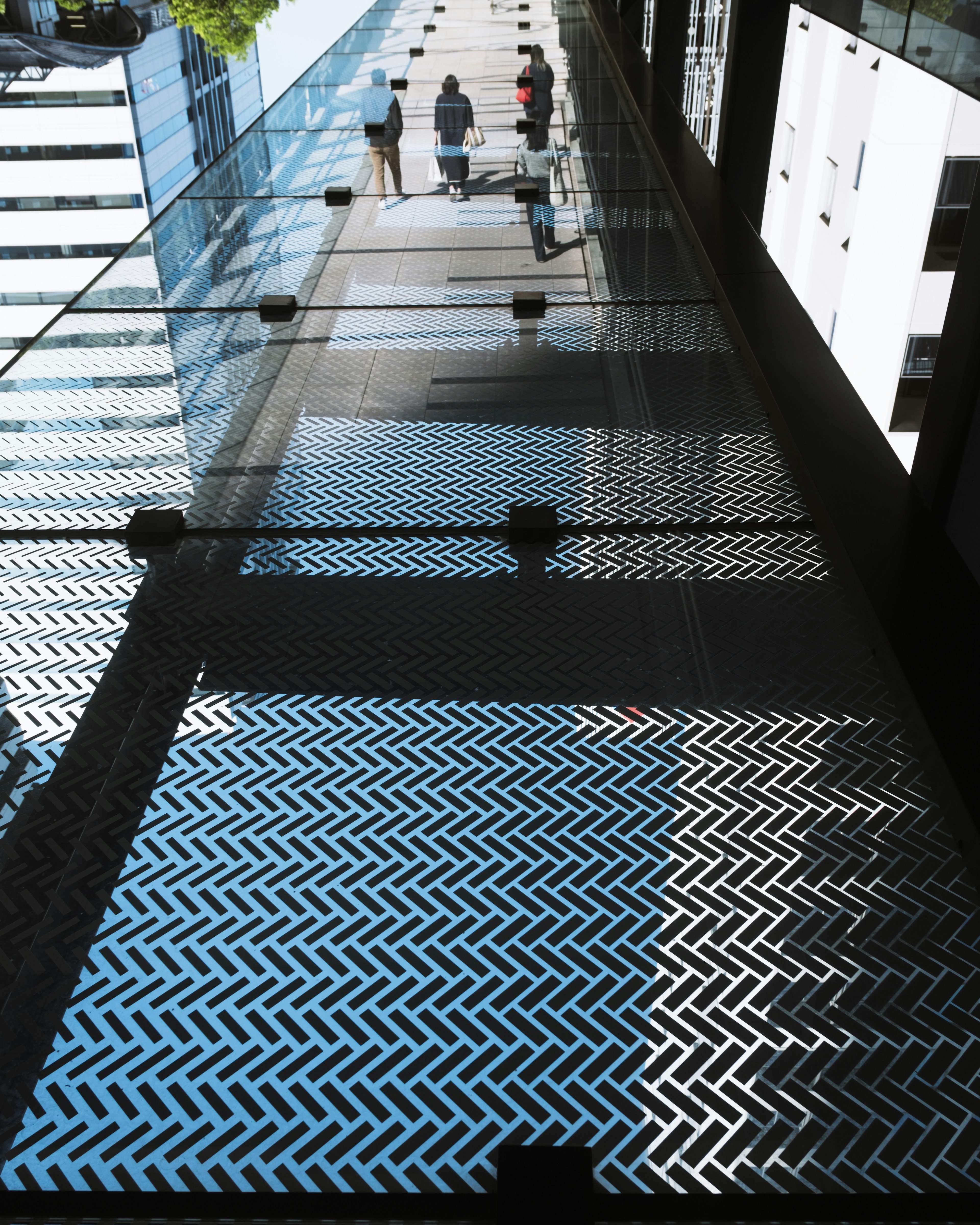 People walking on a glass walkway with metallic patterns