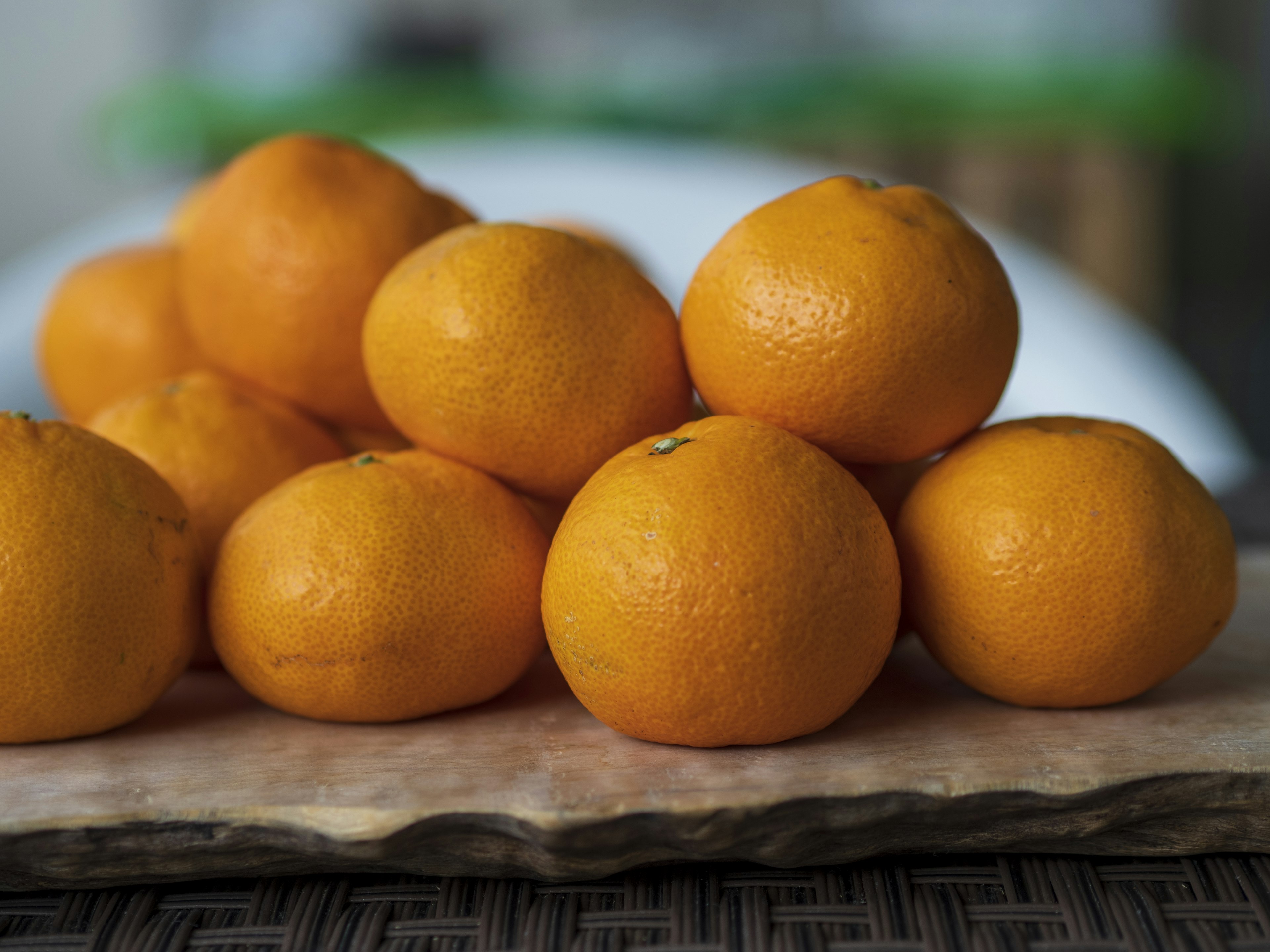 A pile of bright orange mandarins arranged on a wooden board