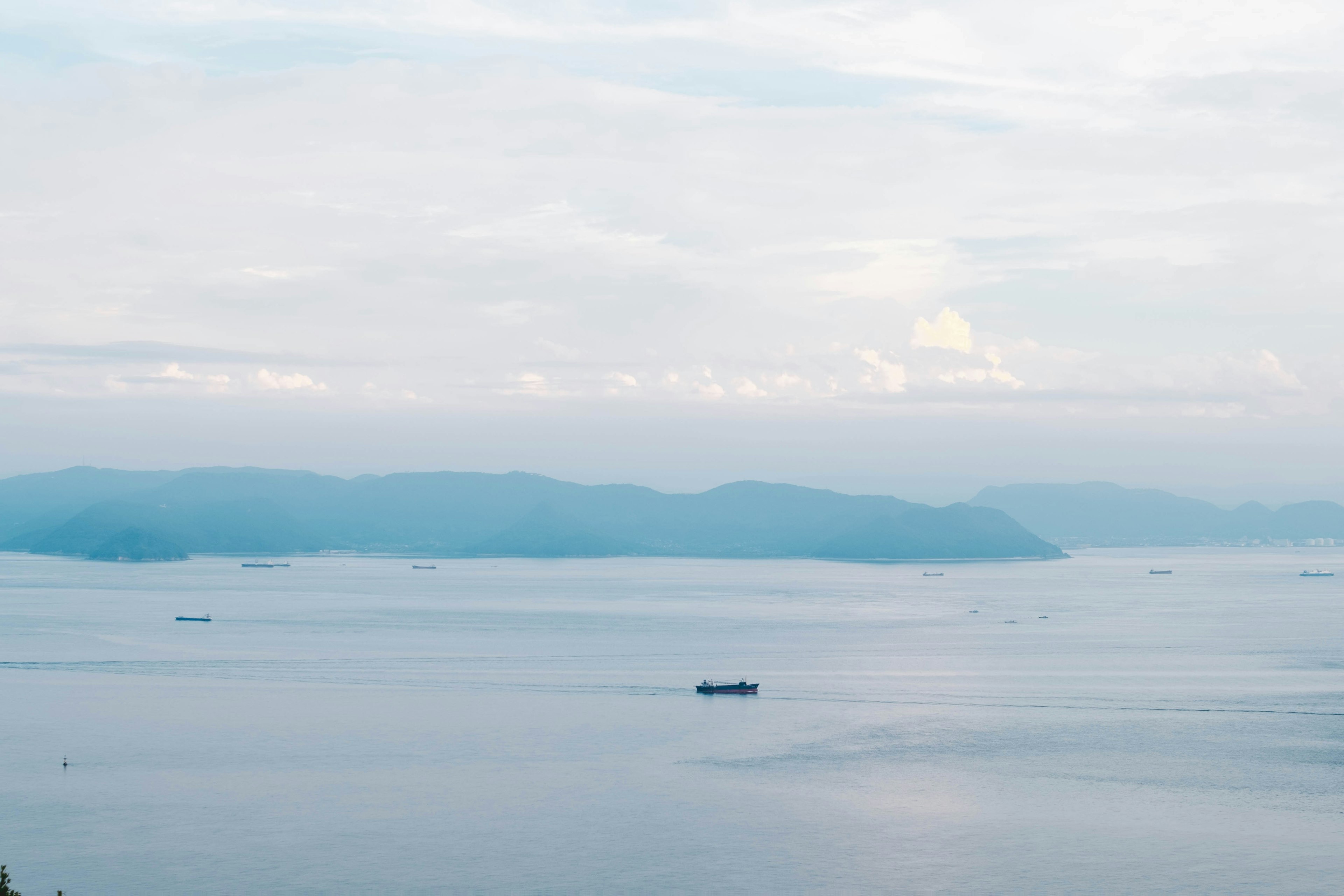 A ship floating on a blue sea with distant mountains