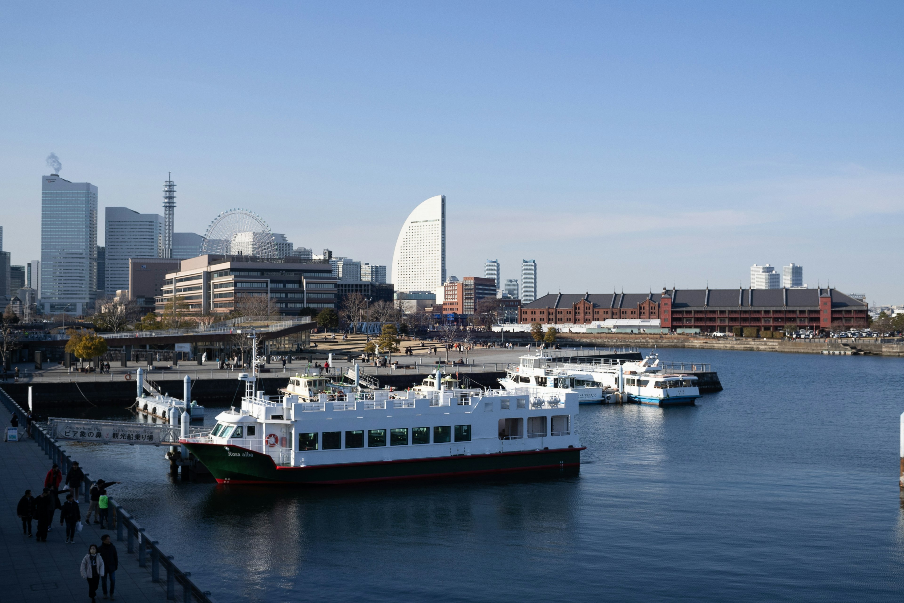 Blick auf weiße Boote im Hafen von Yokohama mit Wolkenkratzern im Hintergrund