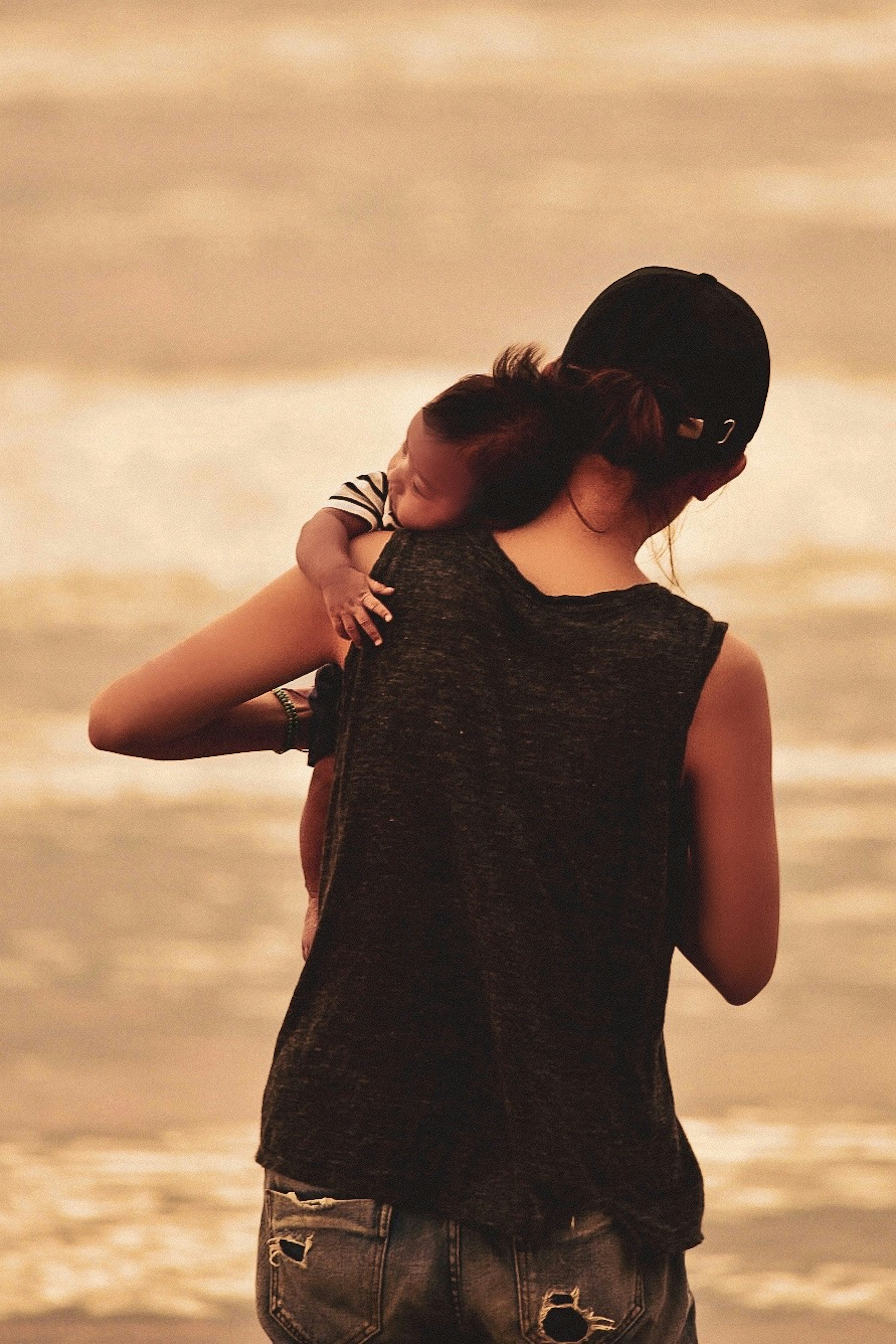 Silhouette of a woman holding a child by the beach