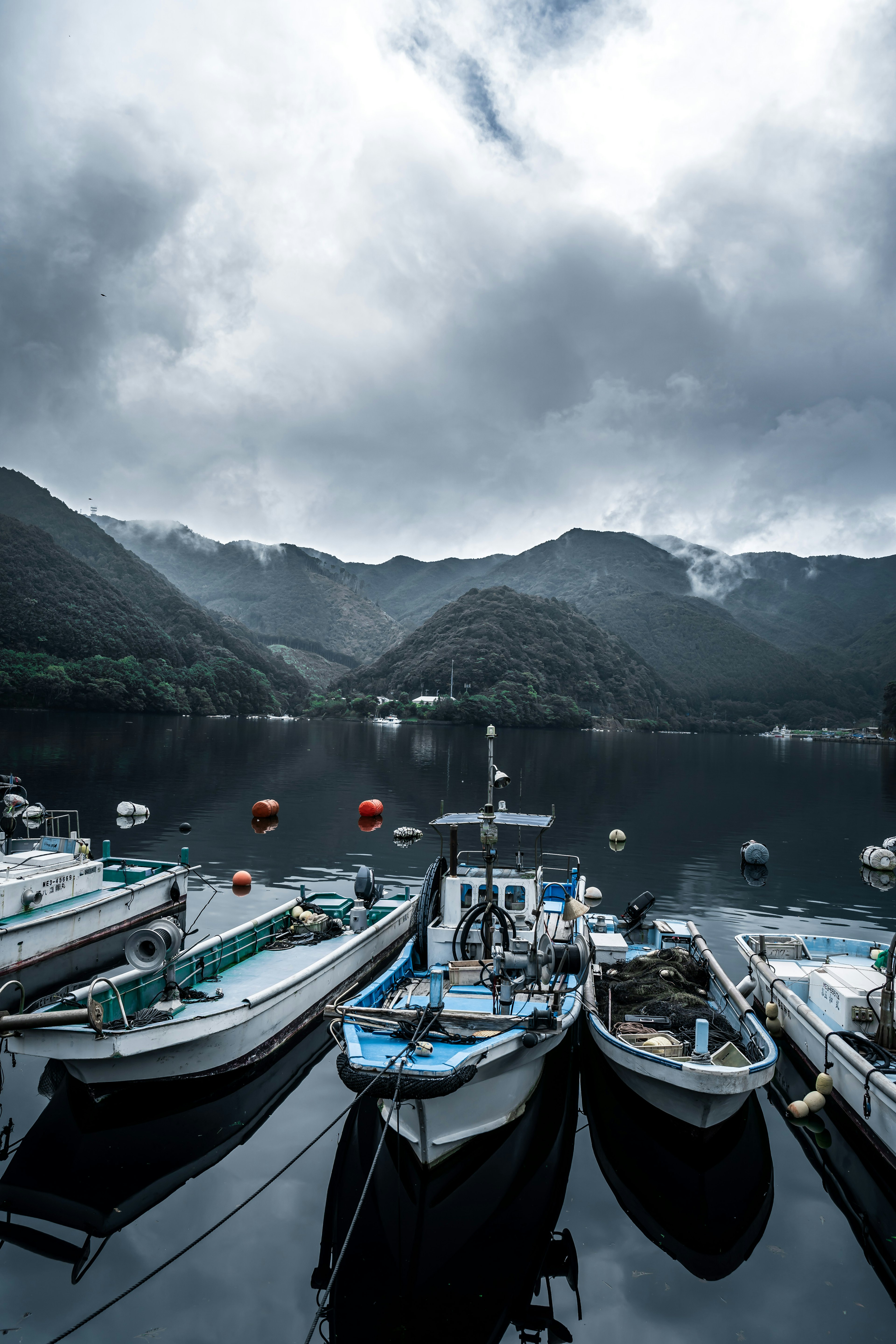 Botes de pesca atracados en un puerto tranquilo rodeado de montañas