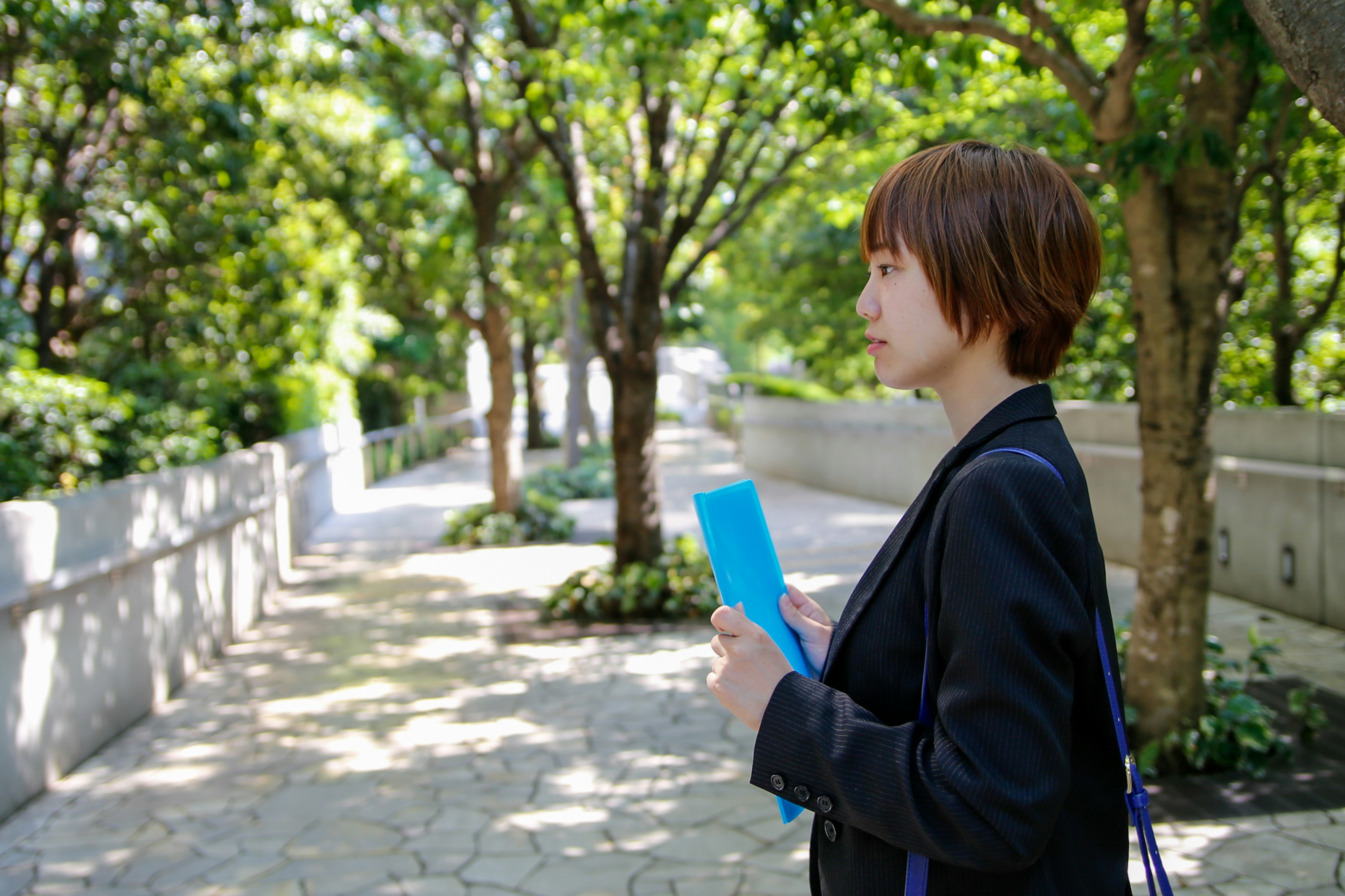 Businesswoman holding a blue file in a lush green park