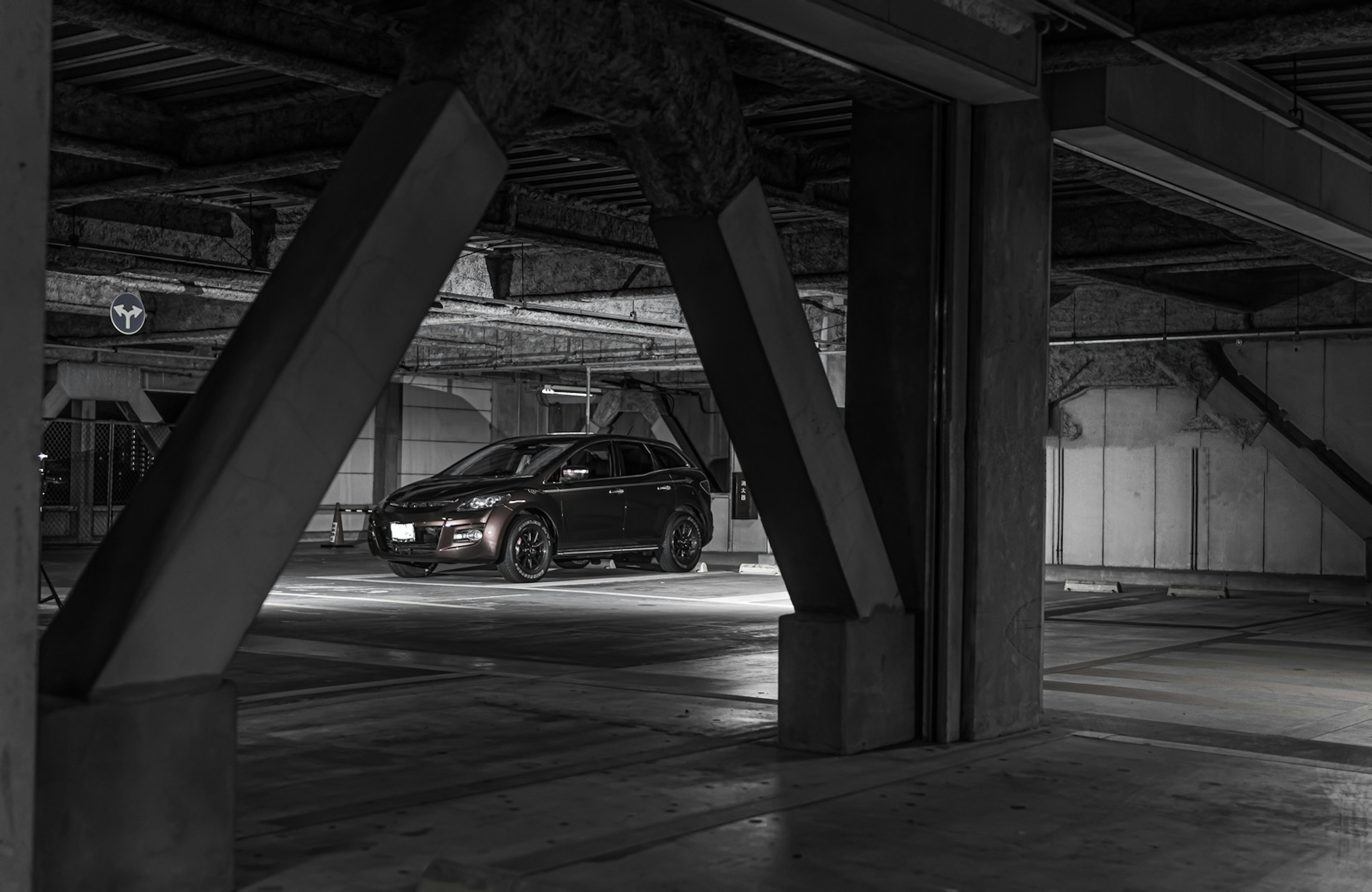 Contraste d'une voiture garée dans un garage noir et blanc avec des éléments structurels