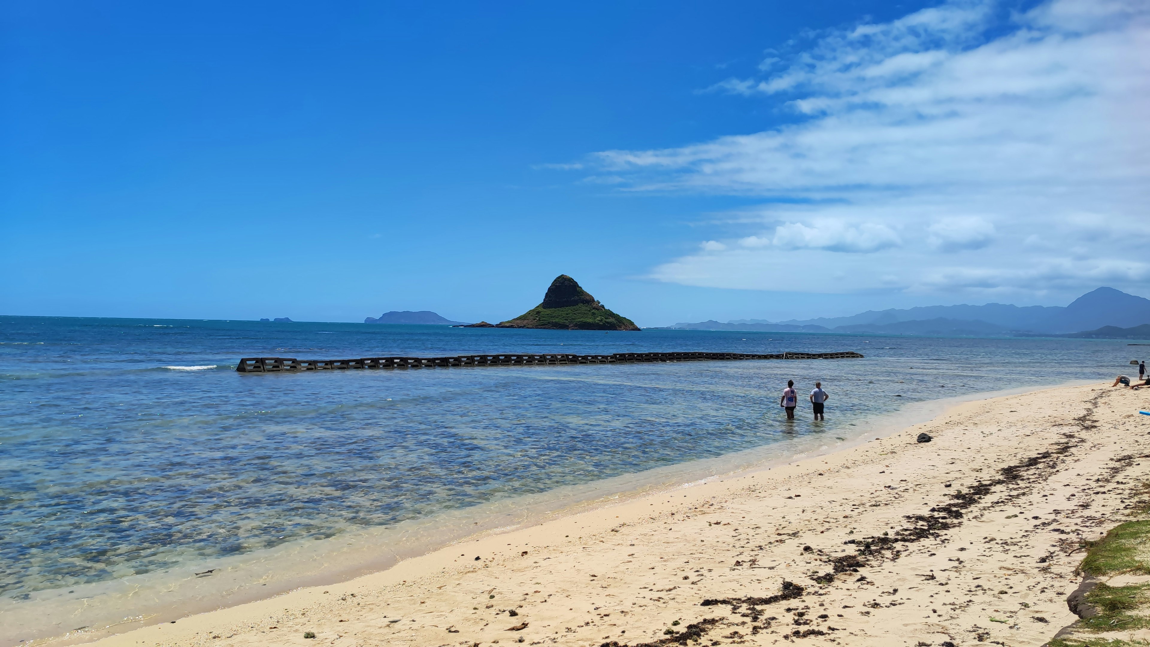 Pantai indah dengan air jernih dan sebuah pulau kecil di kejauhan