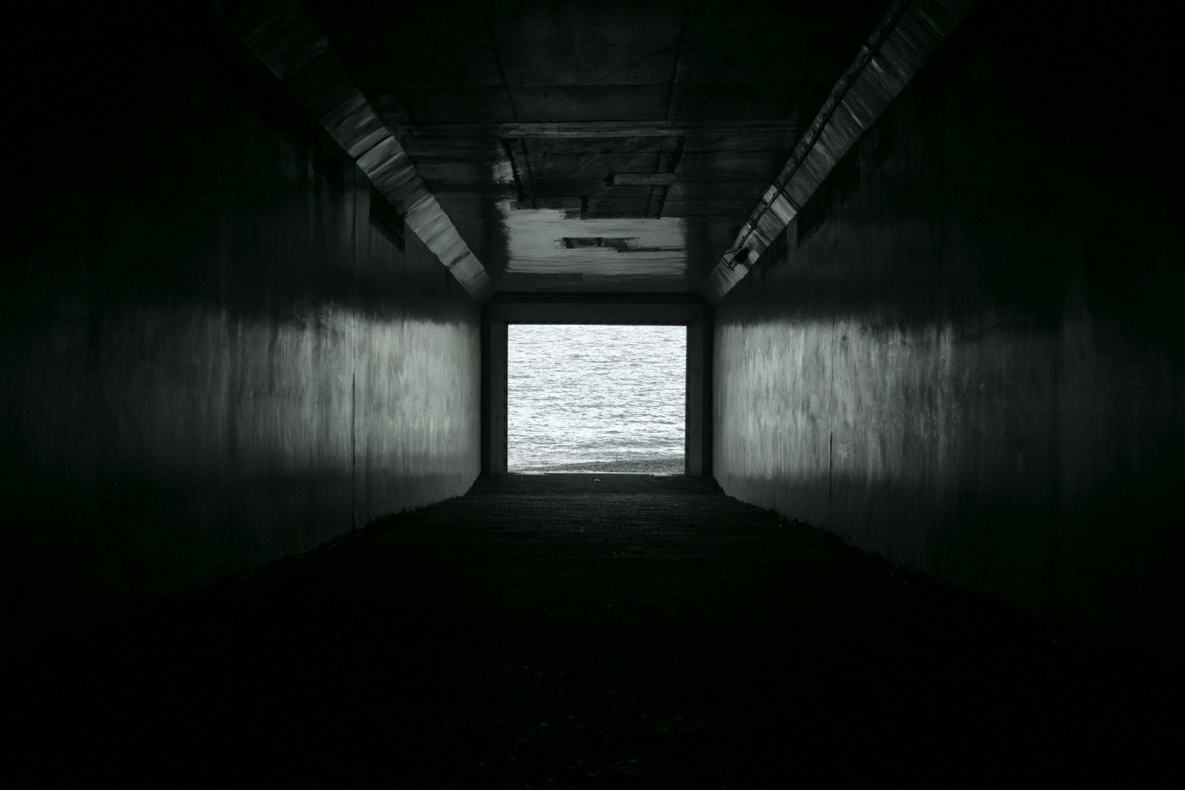 Un tunnel sombre menant à une vue sur la mer