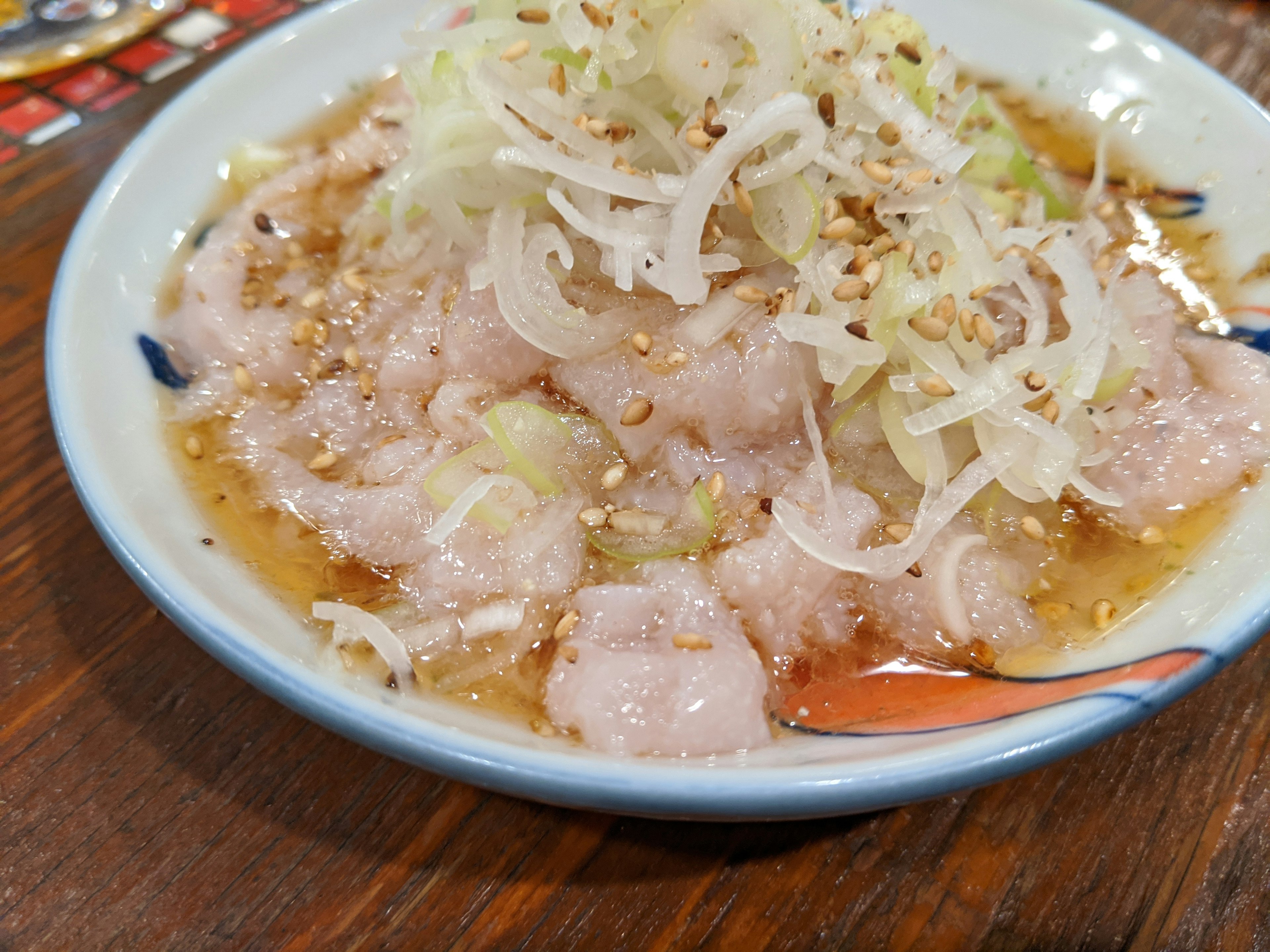 Plato de sashimi cubierto con cebollas verdes finamente rebanadas y semillas de sésamo