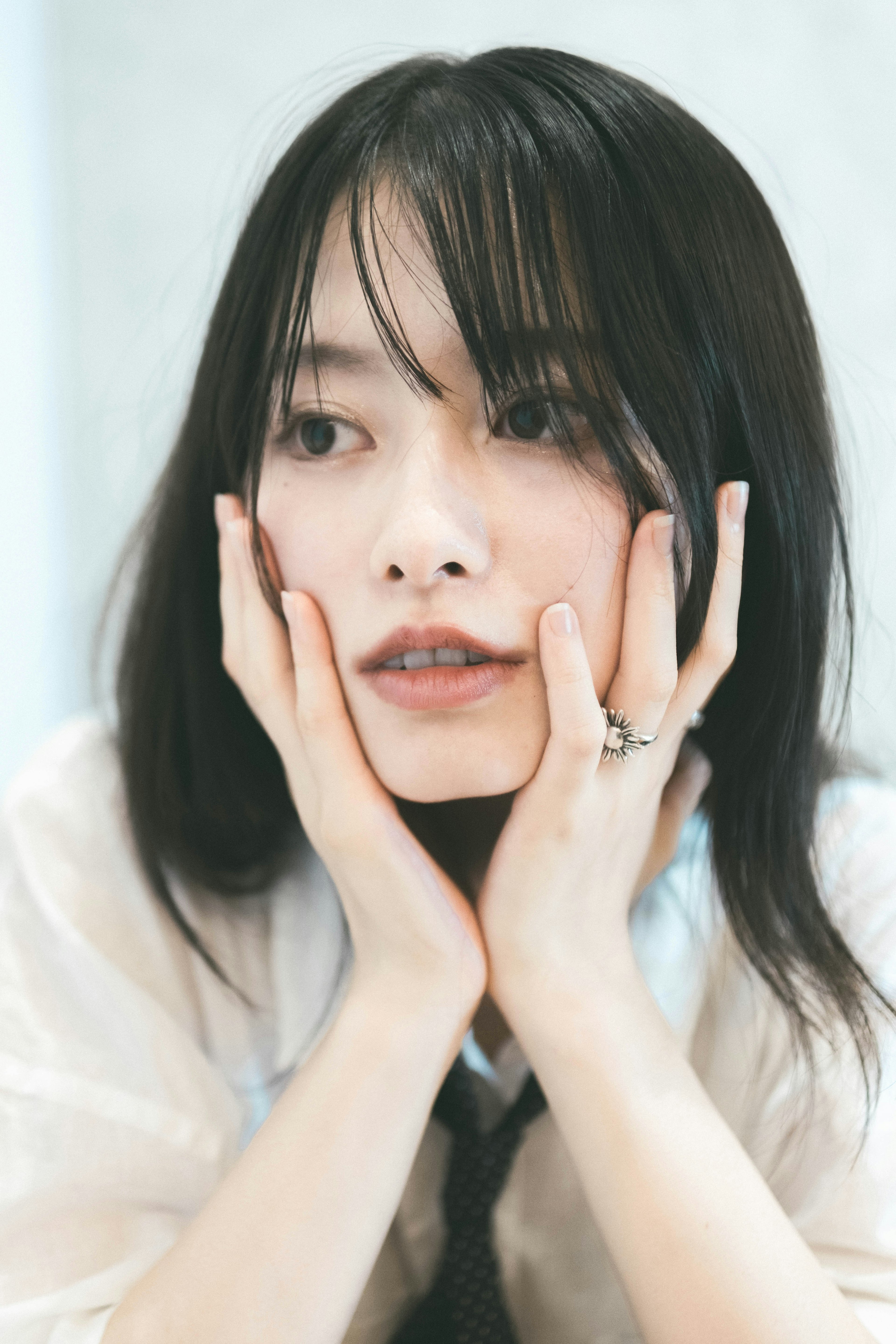 Young woman resting her face on her hands looking thoughtful