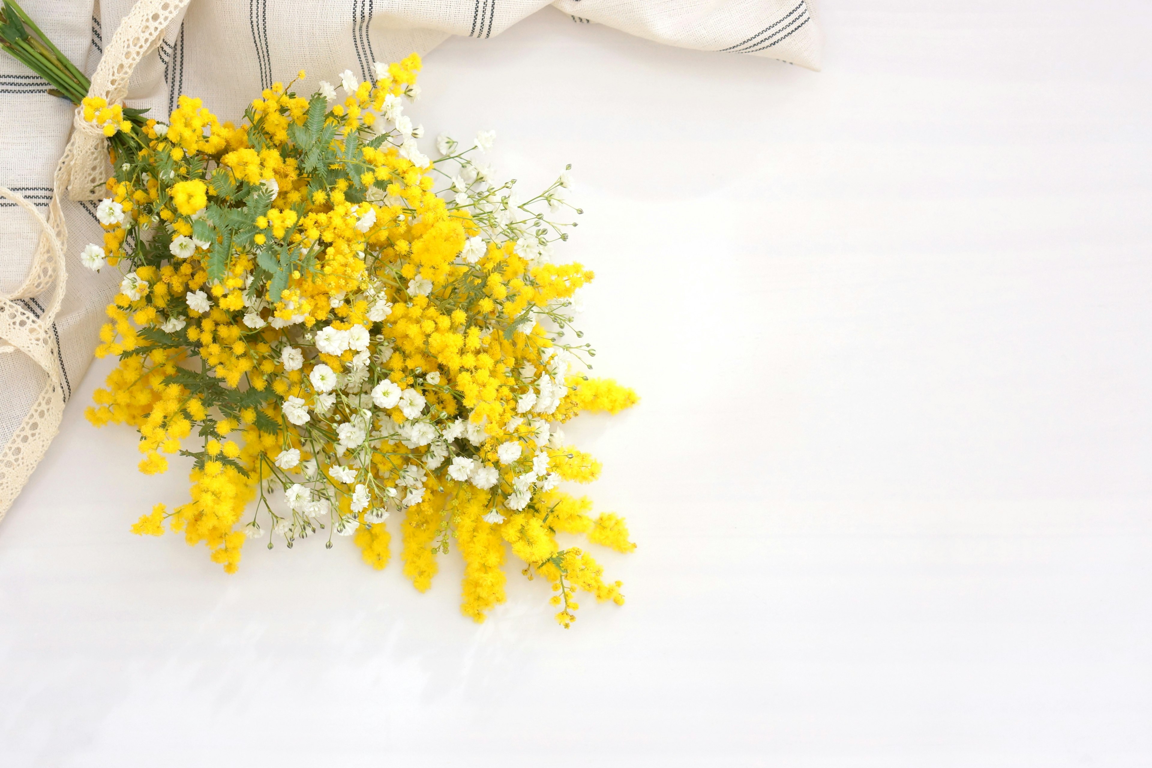 A bouquet of yellow mimosa flowers with white small flowers arrangement