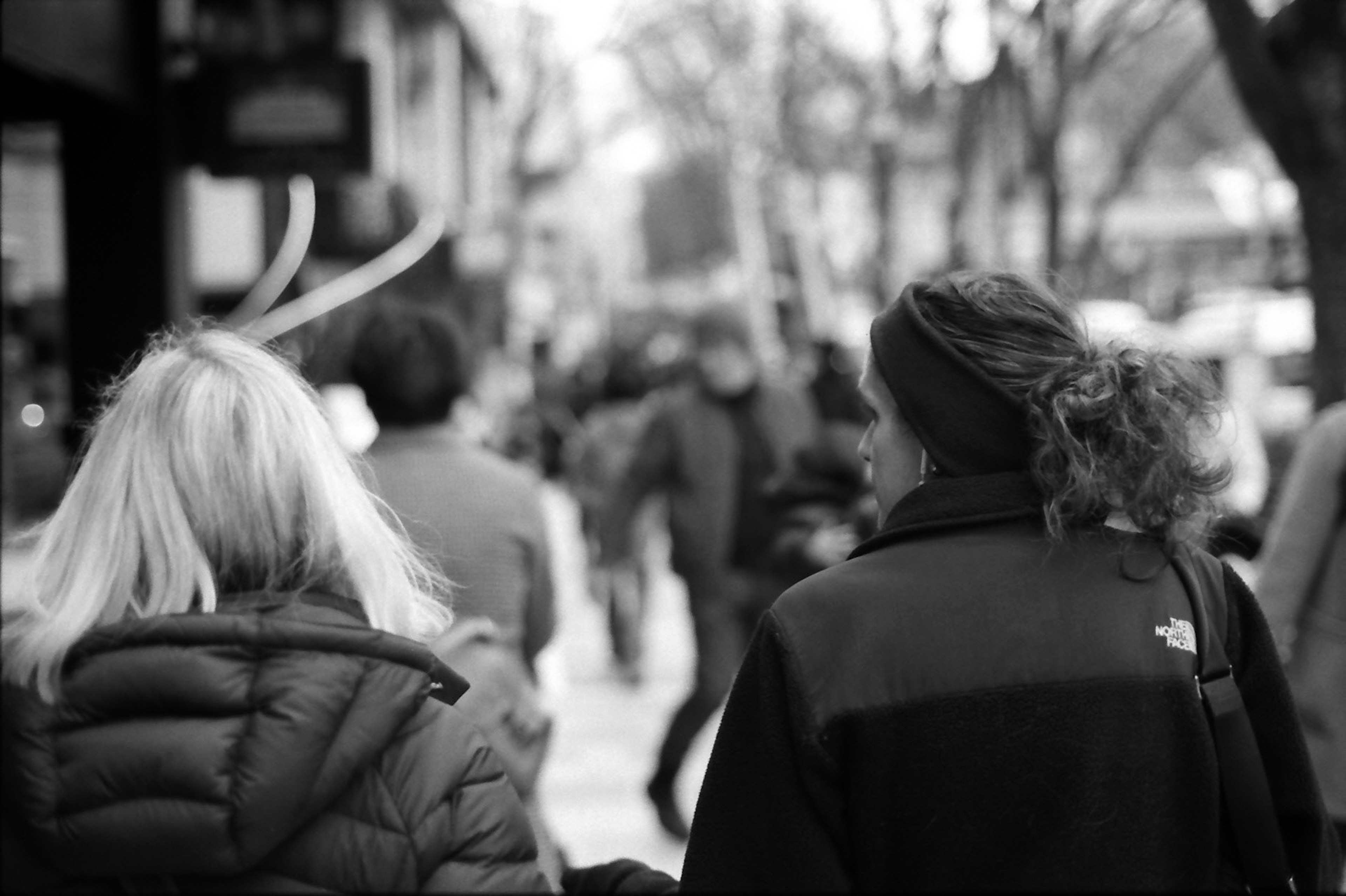 Image en noir et blanc d'une foule dans la ville avec deux femmes qui s'éloignent