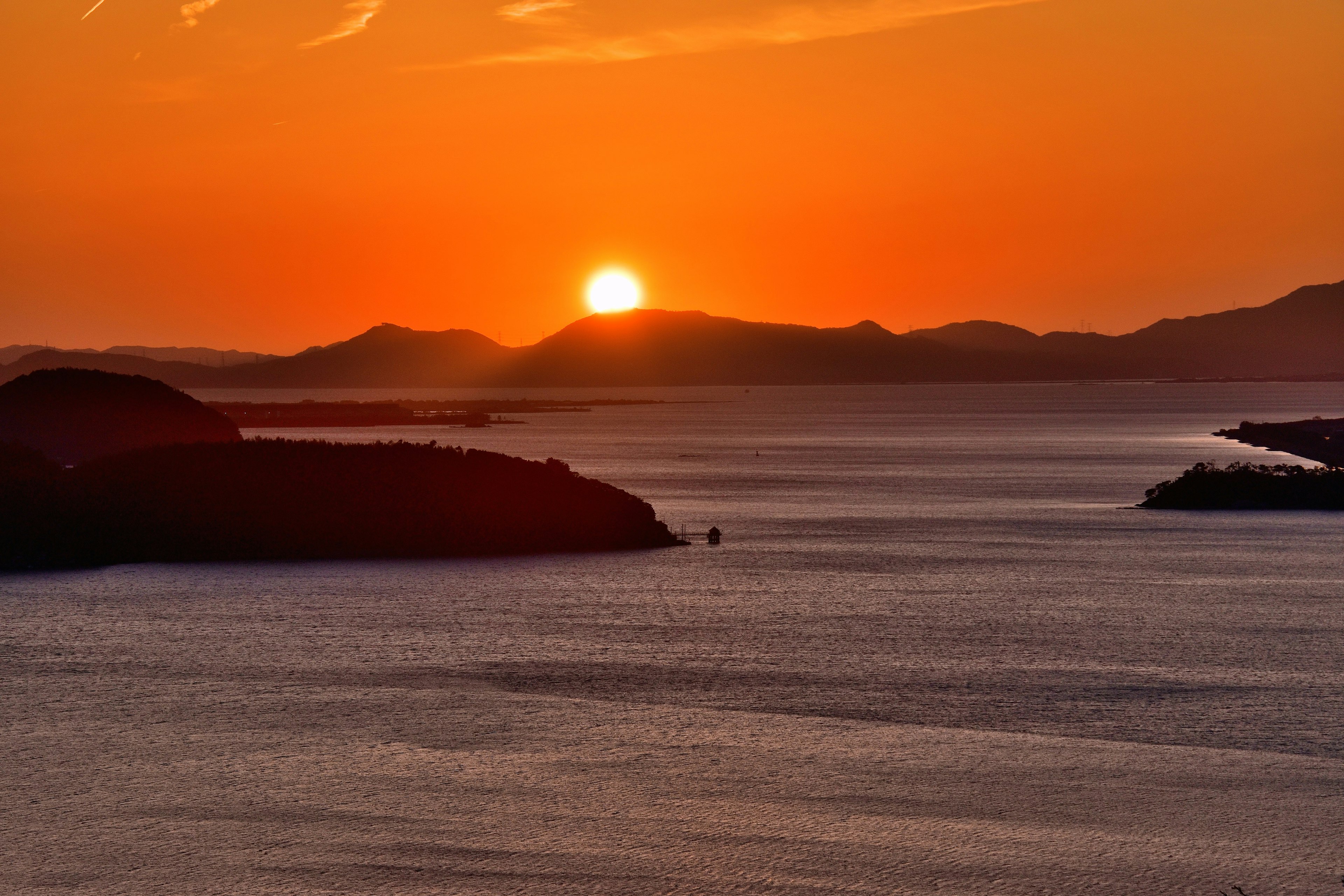 Scenico tramonto sull'oceano con montagne lontane e acque calme