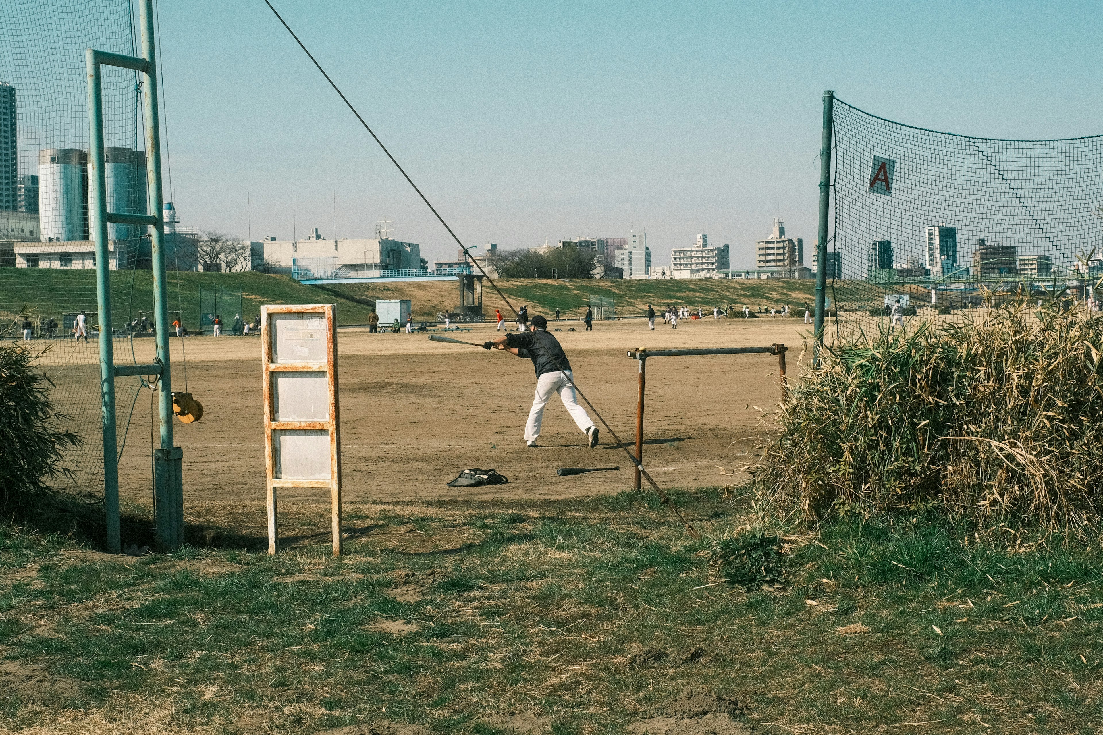 Joueur balançant une batte sur un terrain de baseball avec une ville en arrière-plan