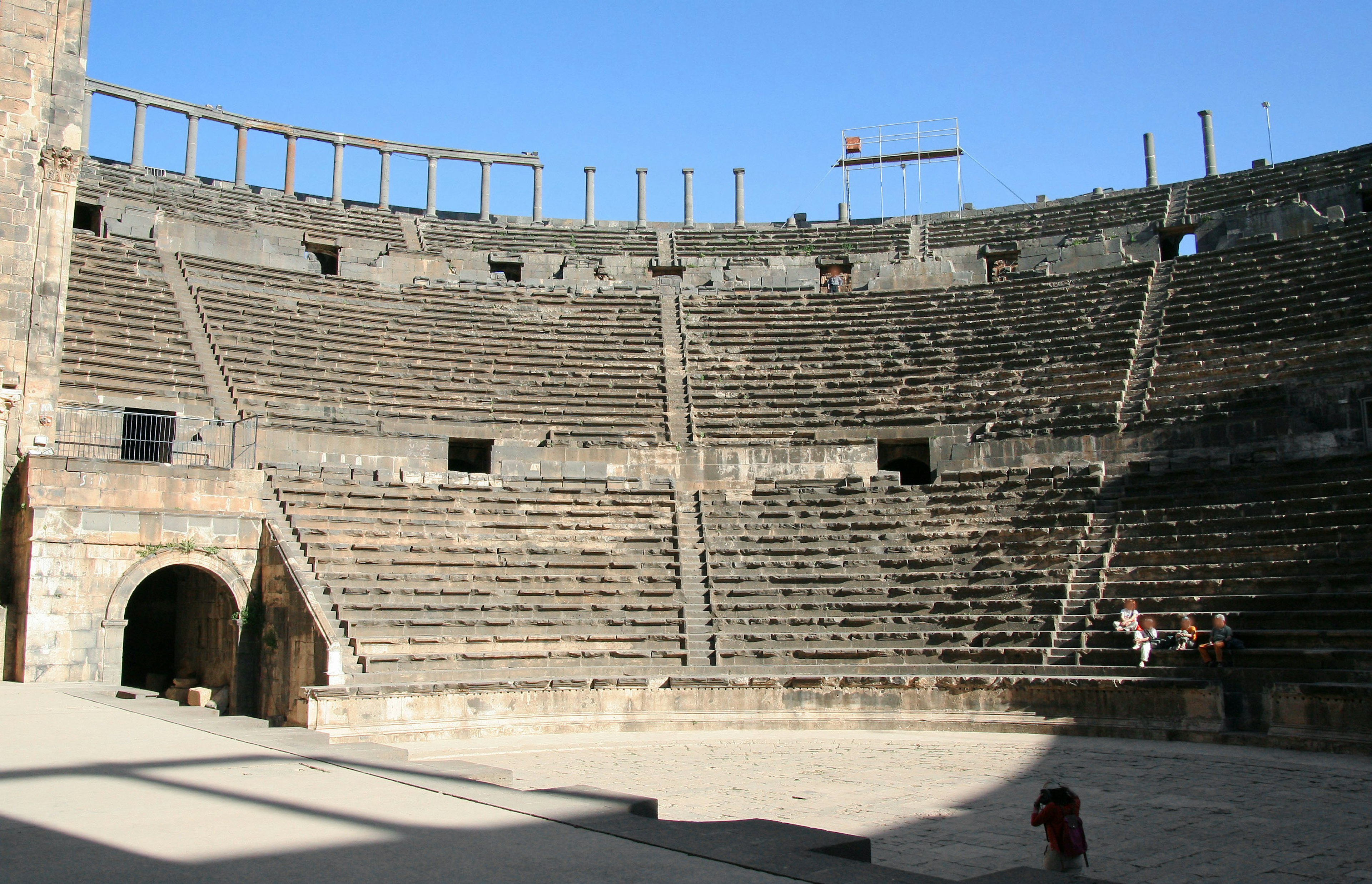 Vue intérieure d'un amphithéâtre ancien avec des sièges en pierre et un ciel bleu clair