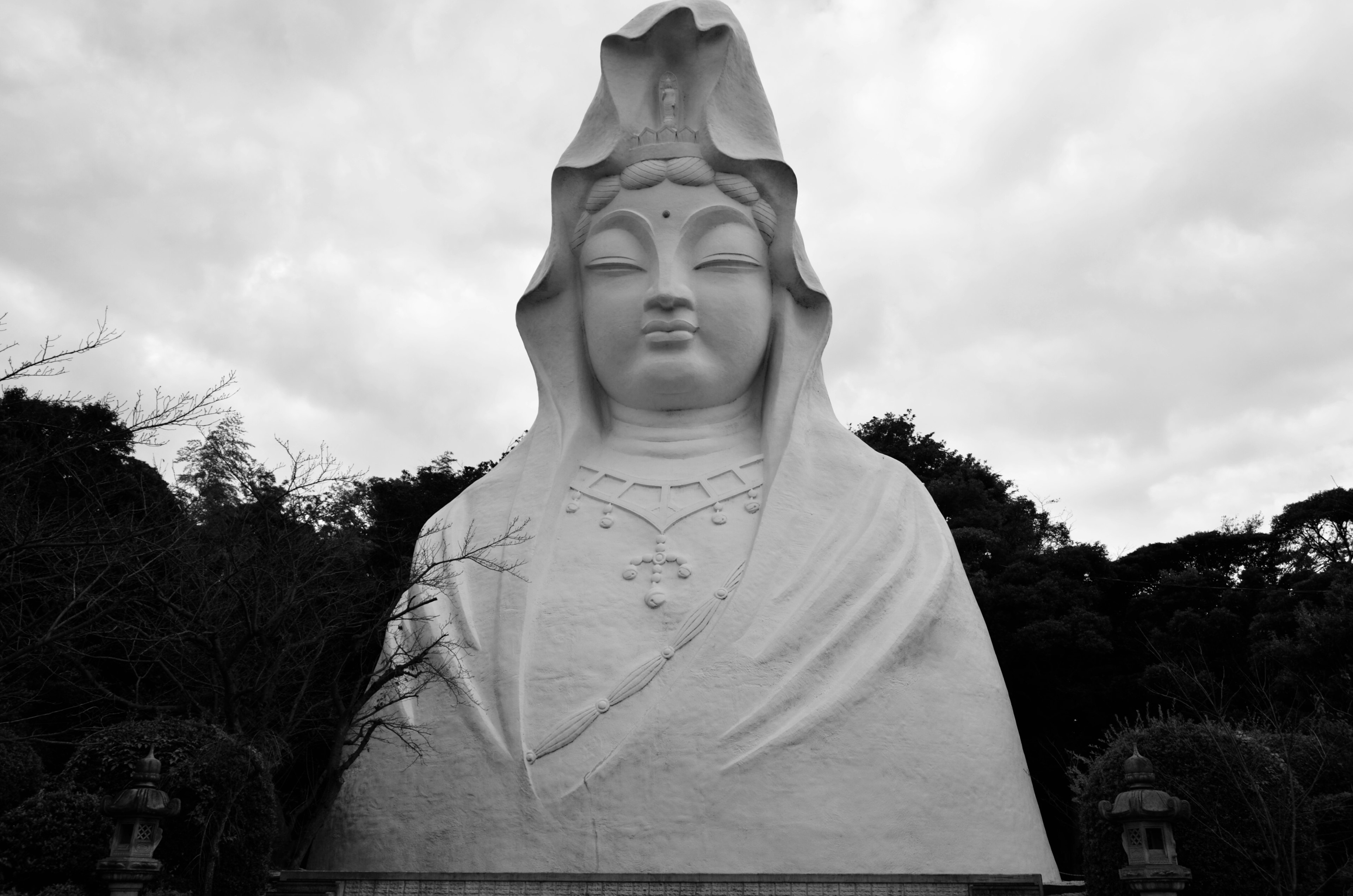 Large white Kannon statue in a serene outdoor setting