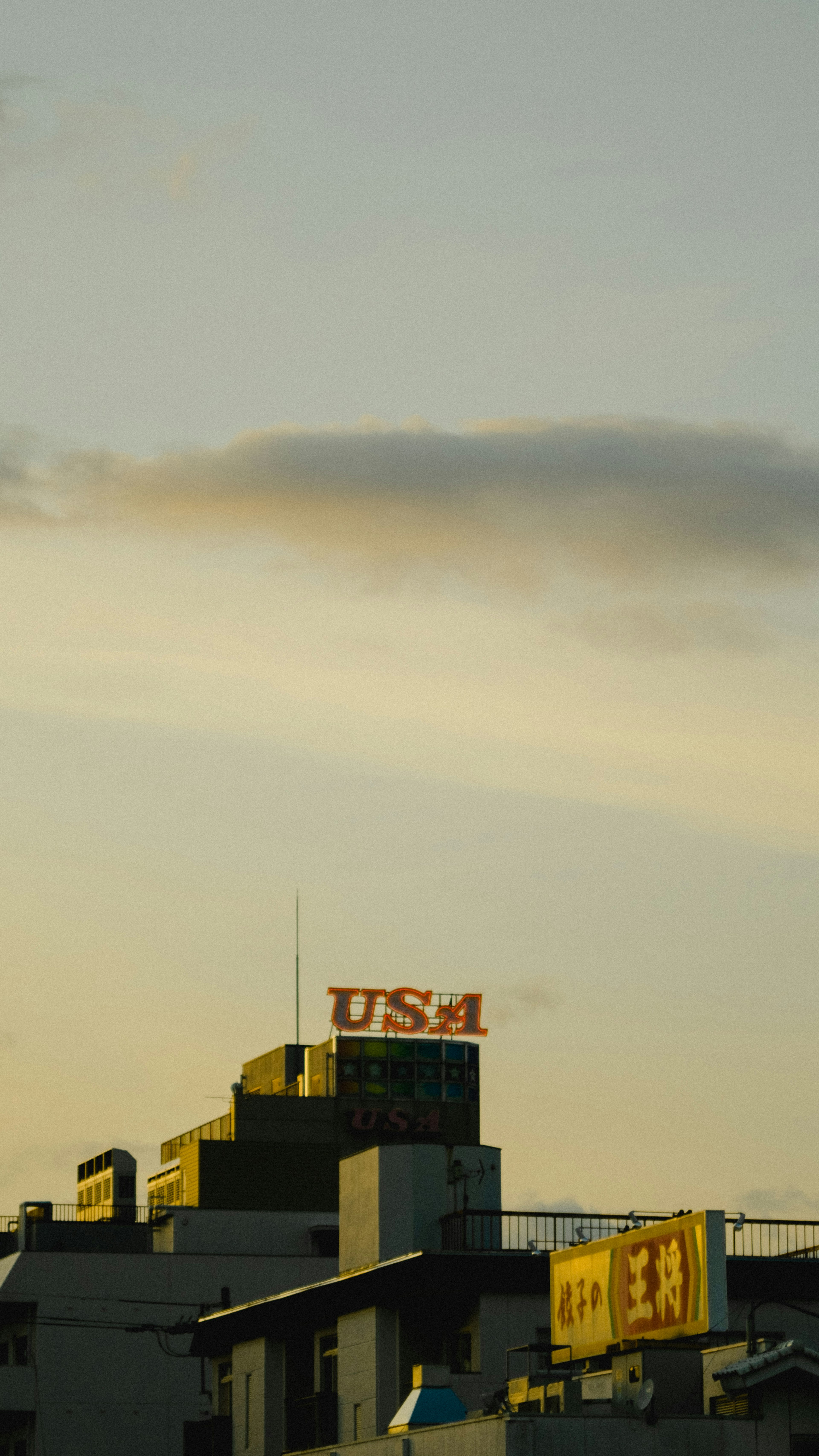 夕焼けの空に浮かぶ建物の上にあるUSAの看板