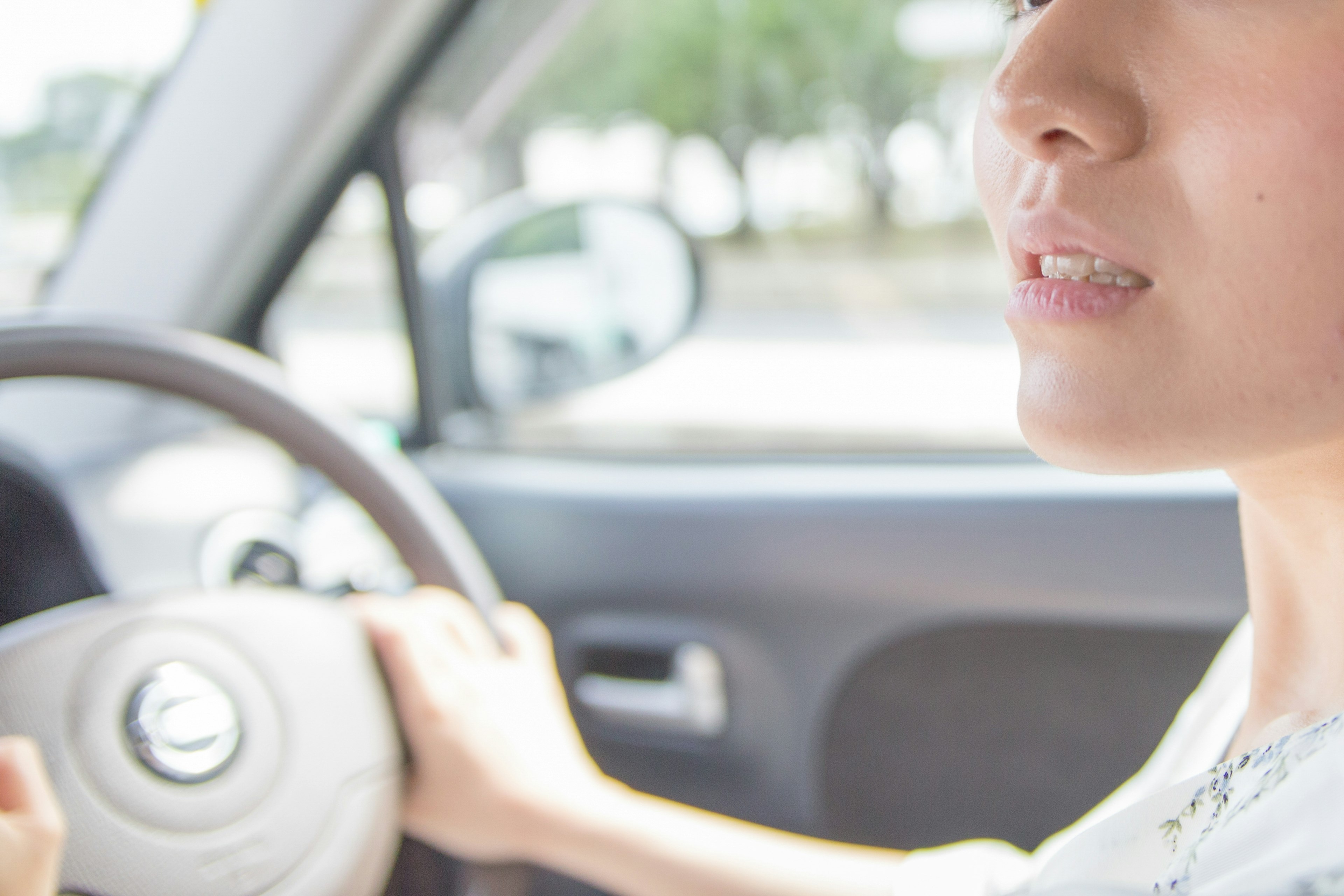 Gambar close-up wanita yang mengemudikan mobil dengan fokus pada wajahnya