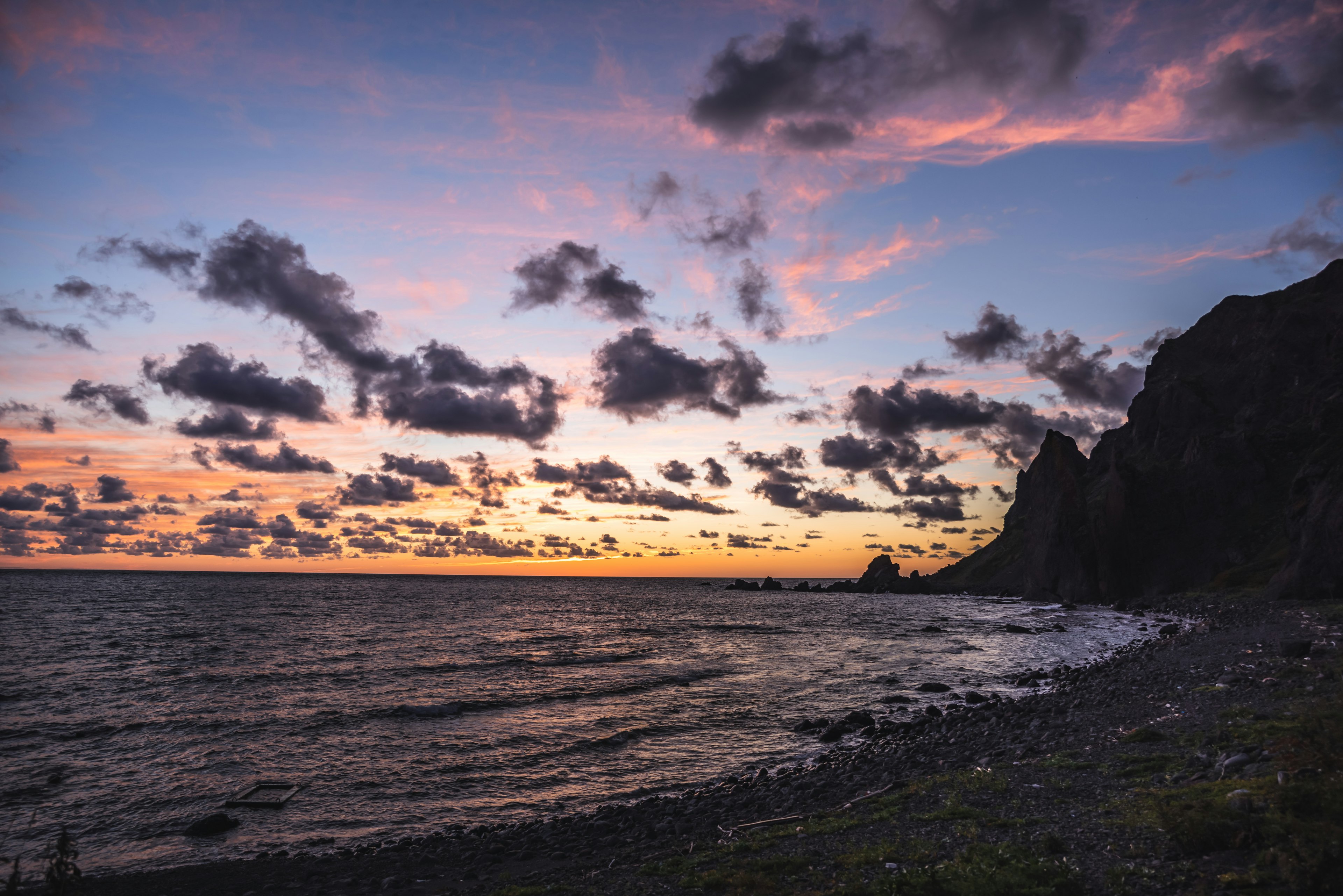 Scena costiera al tramonto con nuvole e scogliere rocciose